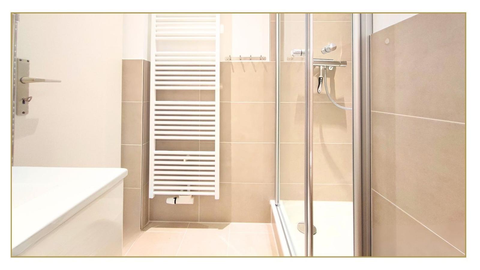 Badezimmer mit Dusche, Badewanne und Heizkörper an der Wand.