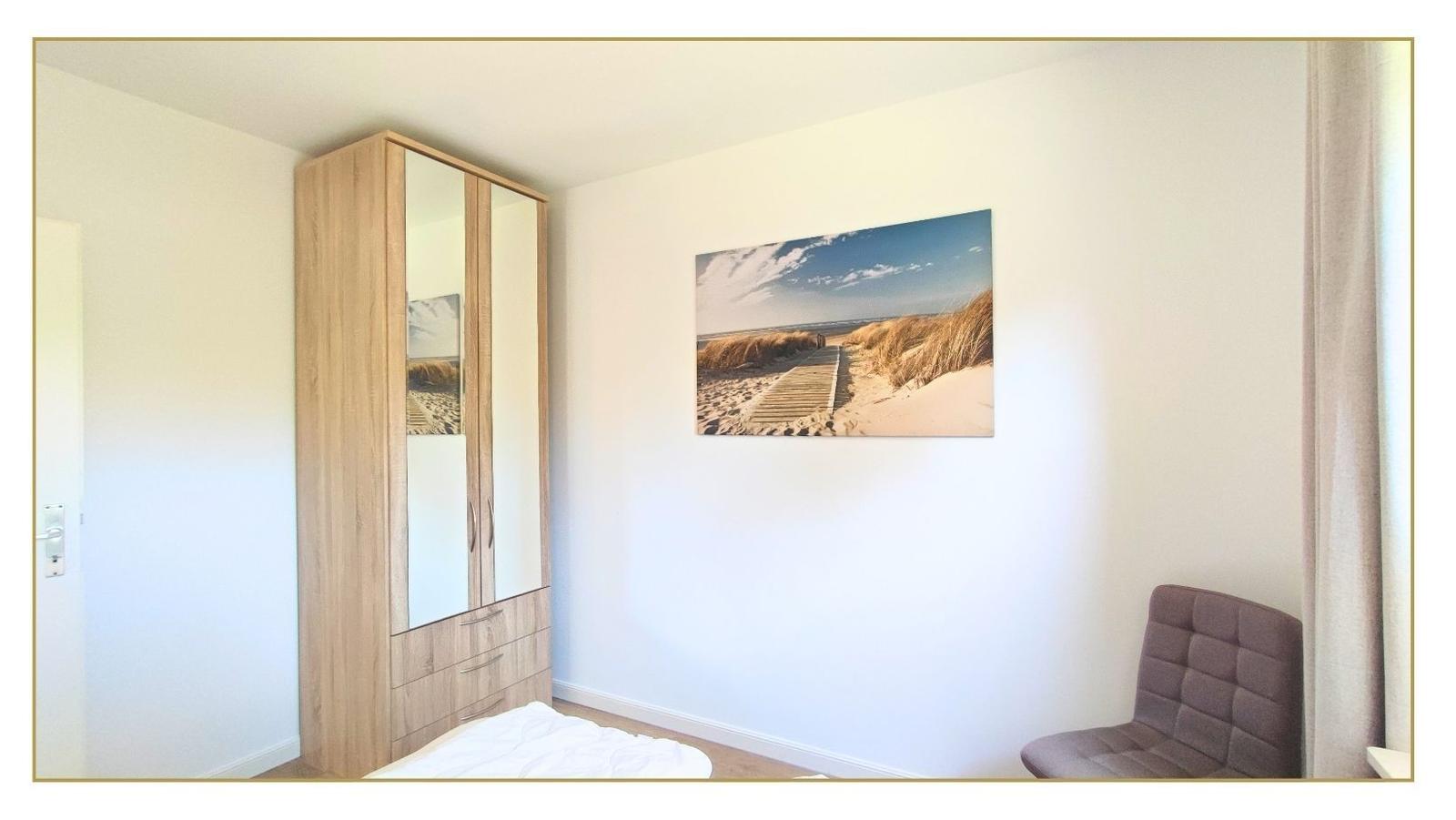 Schlafzimmer mit Kleiderschrank, Wandbild und Sessel