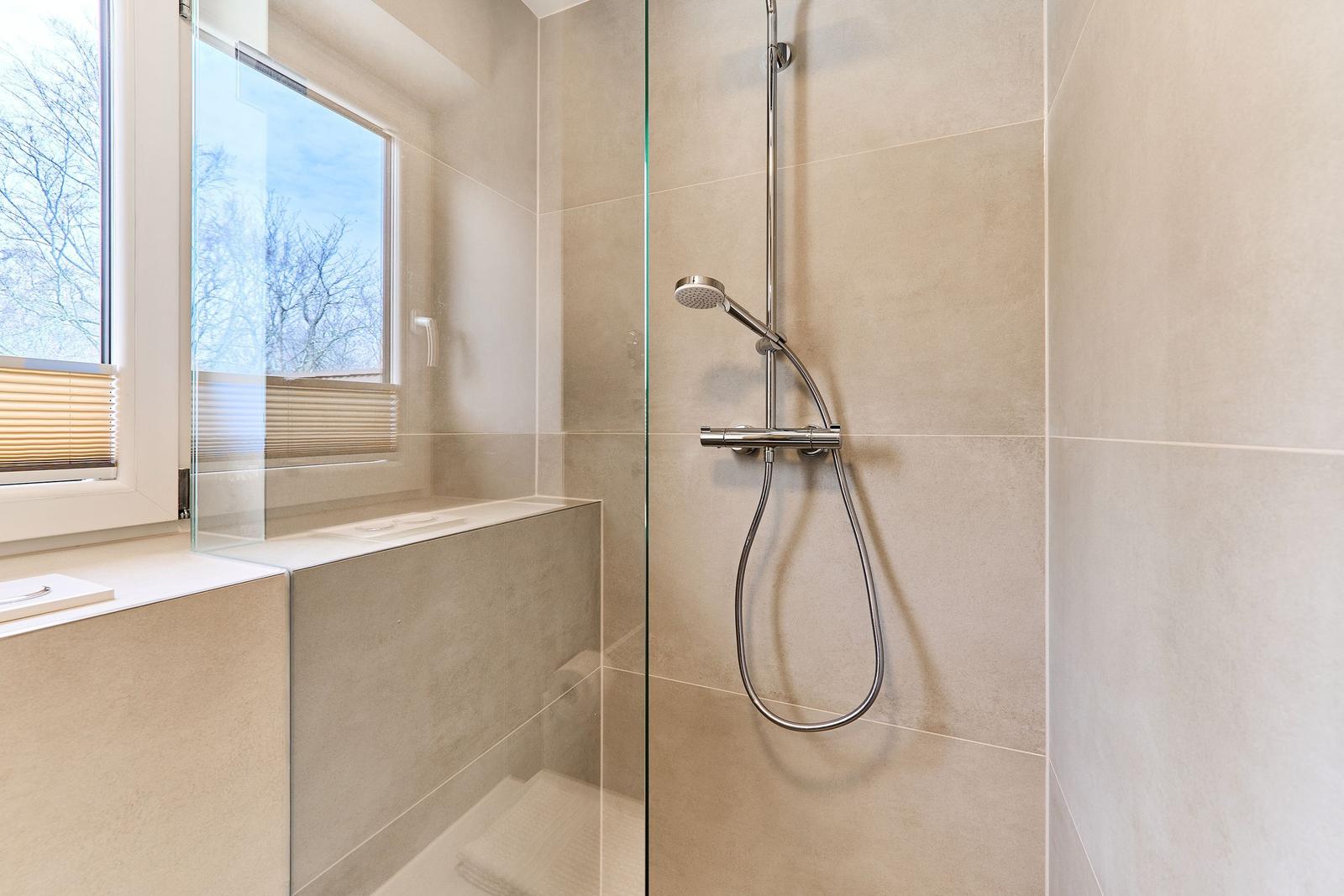 Dusche mit Glaswand, Fenster und Badewanne