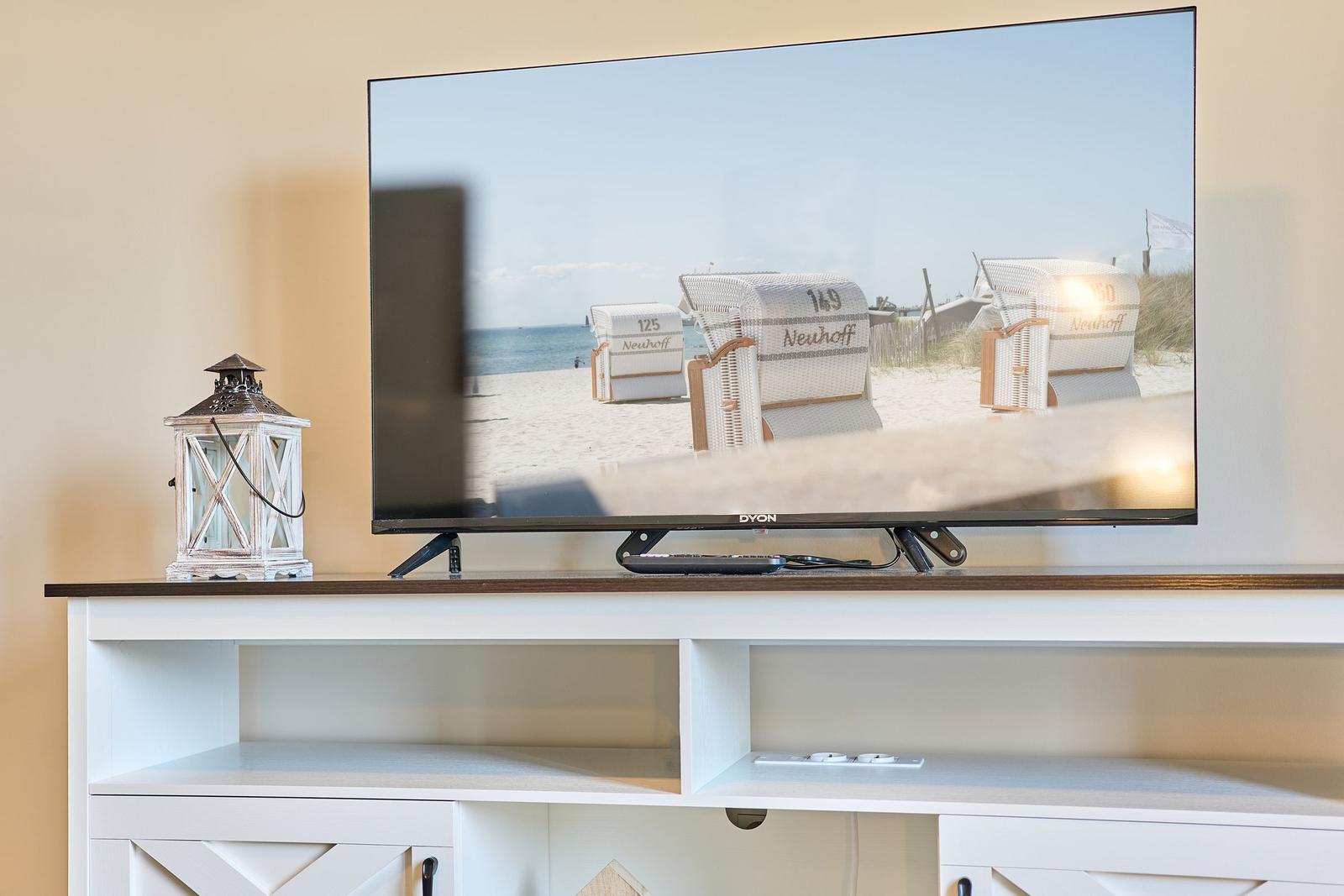 TV auf weißen Schrank mit Laterne und Strandbild