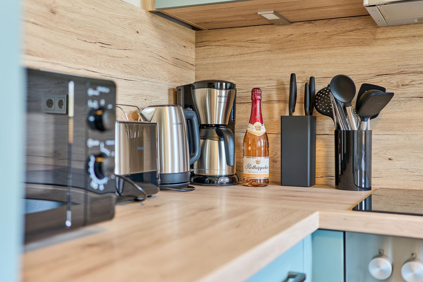 Küchenzeile mit Mikrowelle, Kaffeemaschine, Kanne und Flasche.
