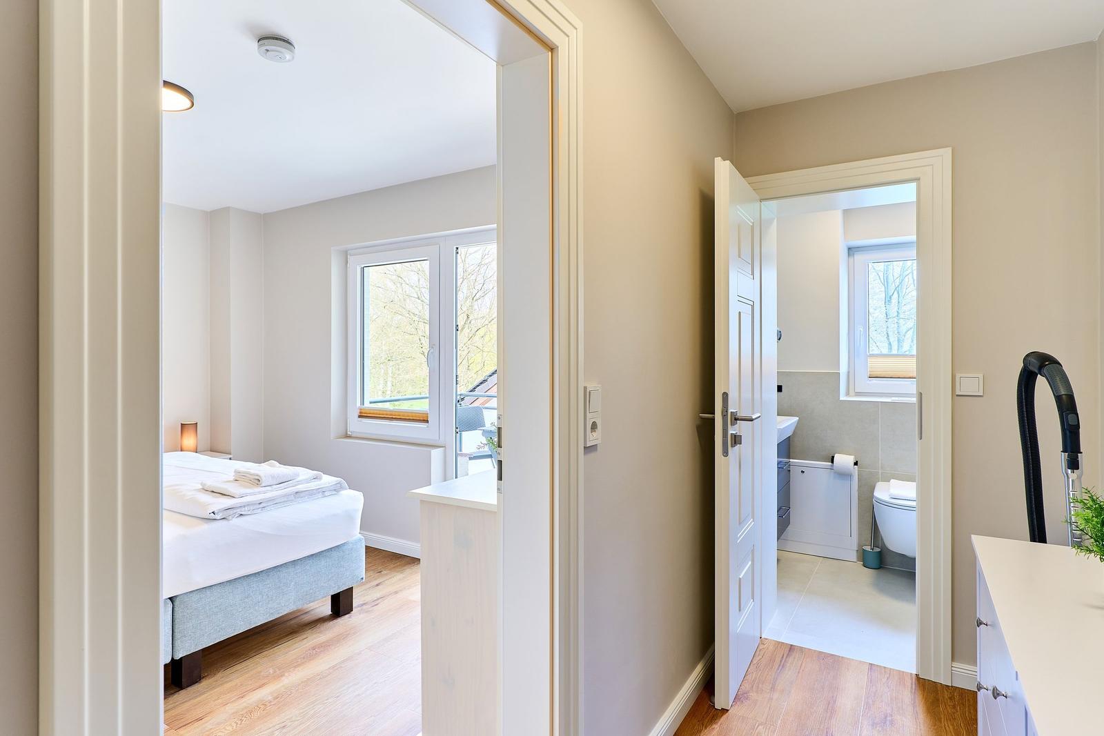 Schlafzimmer mit Bett und Fenster. Nebenraum mit Toilette und Waschbecken.