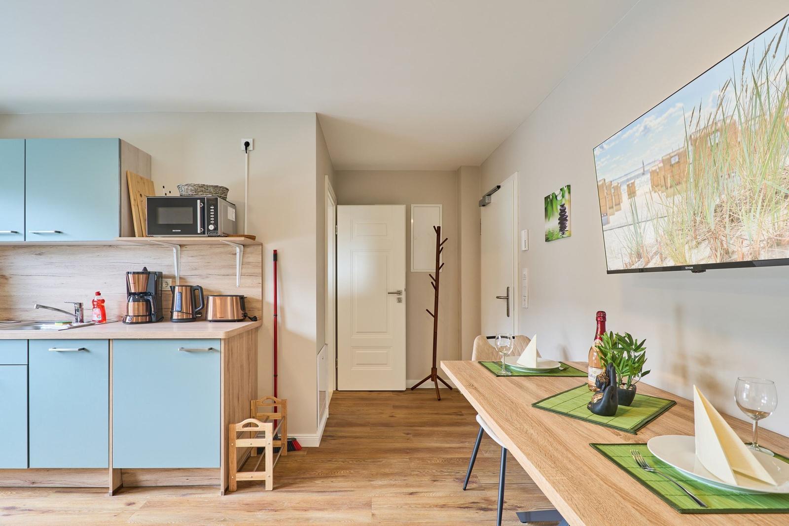 Küche mit Essbereich, TV und Küchenzeile mit Mikrowelle und Kaffeemaschine.