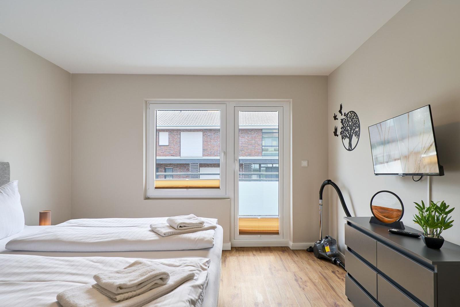 Schlafzimmer mit Doppelschlafcouch, TV, Schrank und Fenster zur Aussicht.