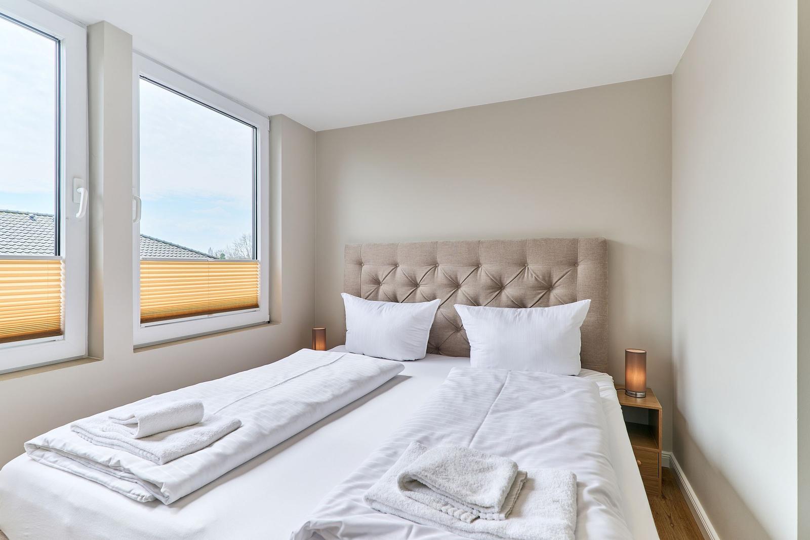 Ein Schlafzimmer mit Doppelbett, Fenstern und Nachttischen.