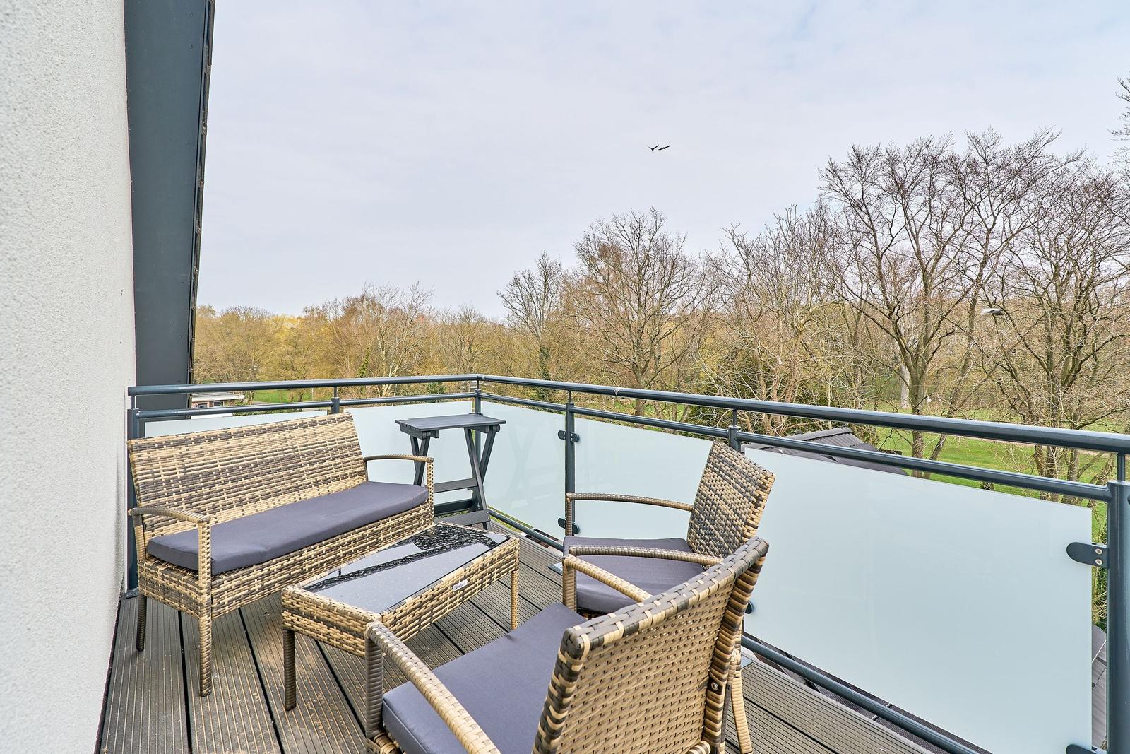 Terrasse mit Sitzgruppe und Blick auf Bäume.