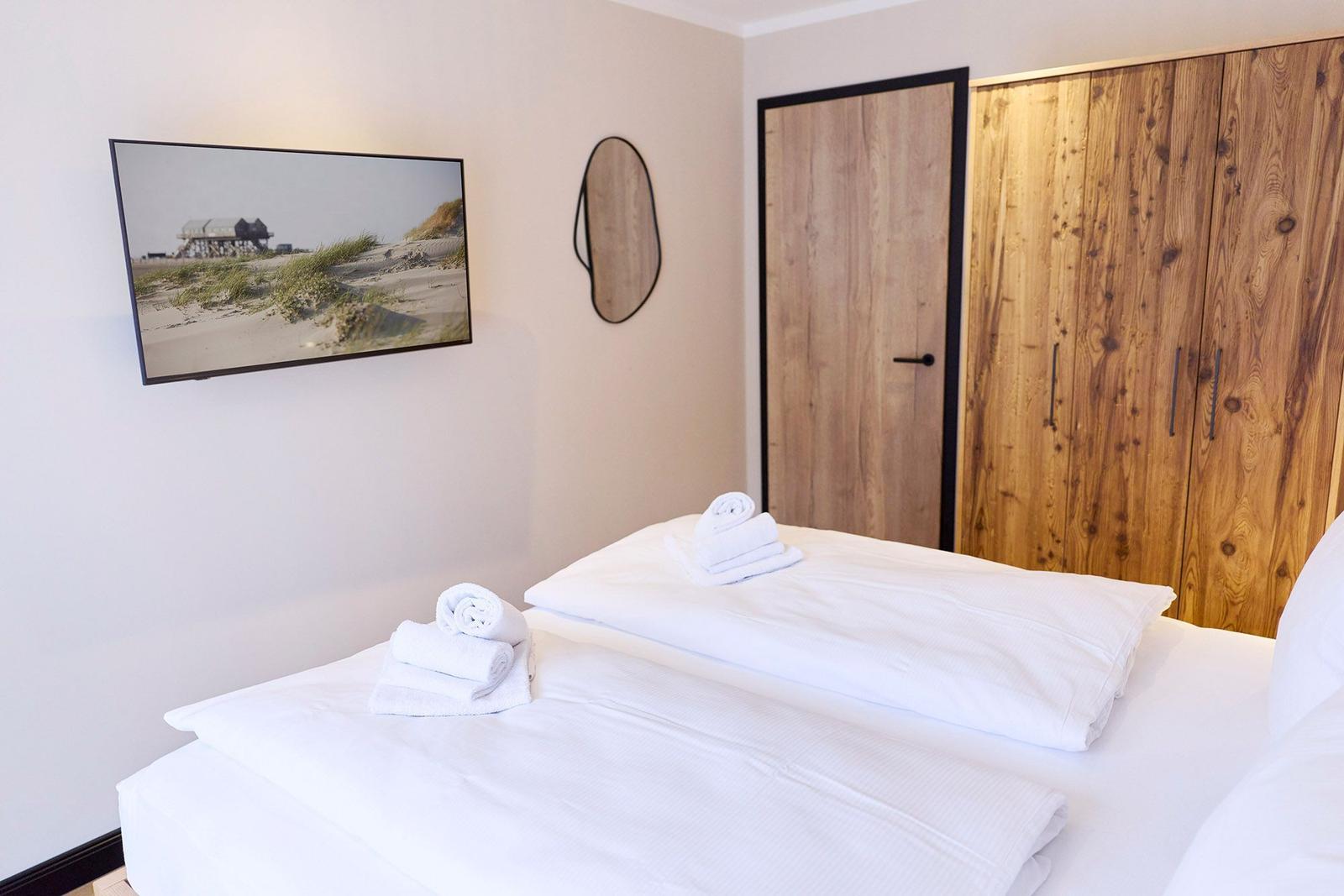 Schlafzimmer mit Bett, Holzschränken und Wandbild