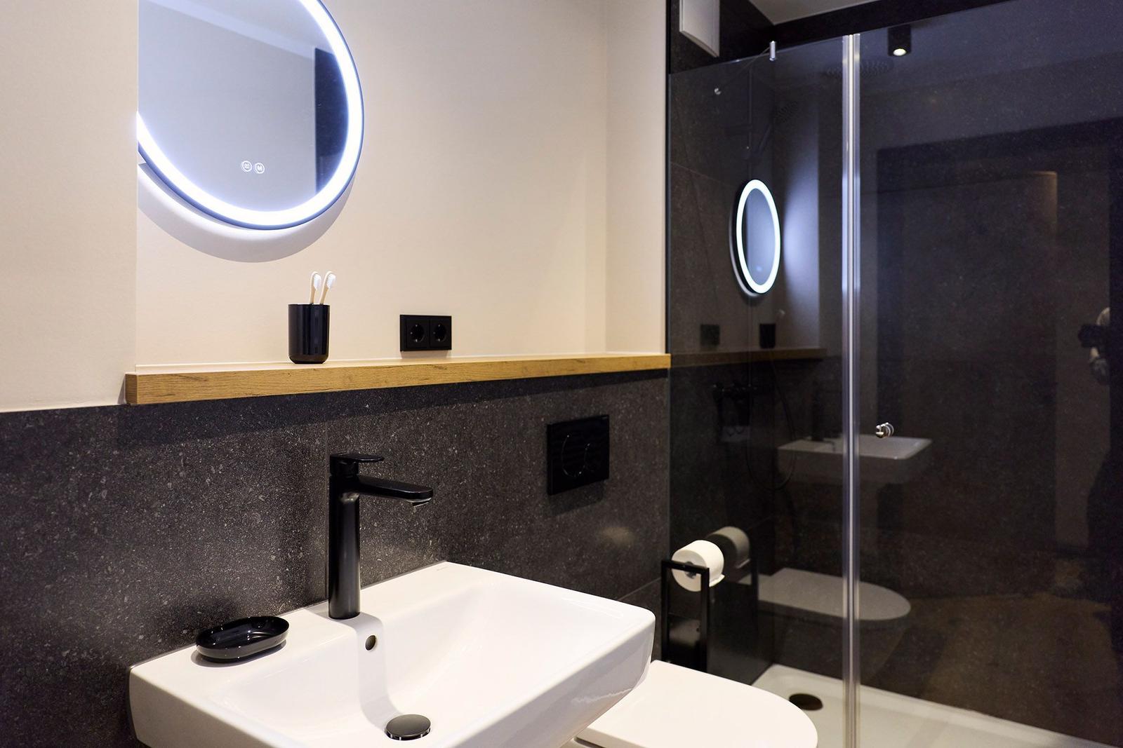 Badezimmer mit Waschbecken, Spiegel und Dusche.