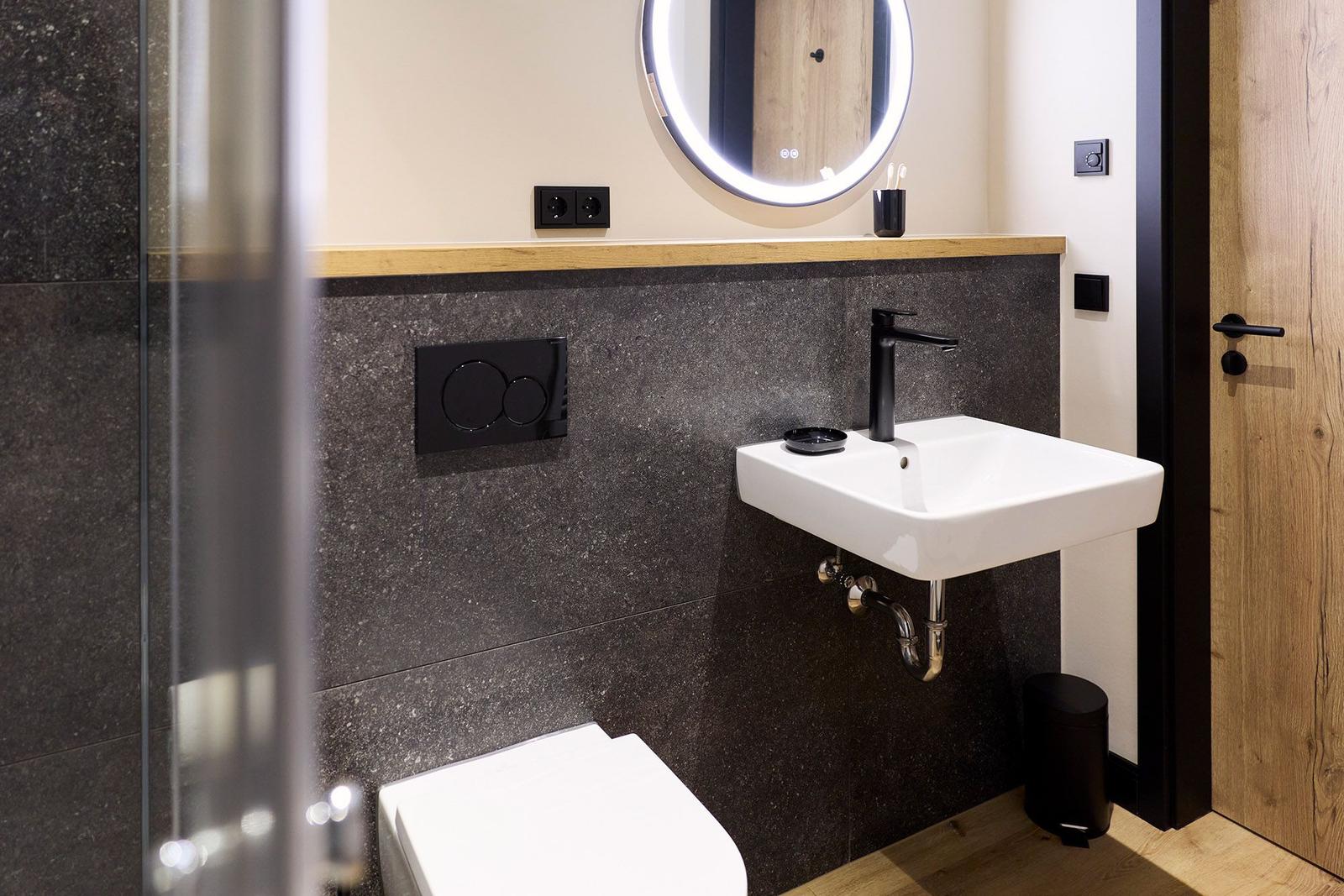 Badezimmer mit Waschbecken, Spiegel und Toilette