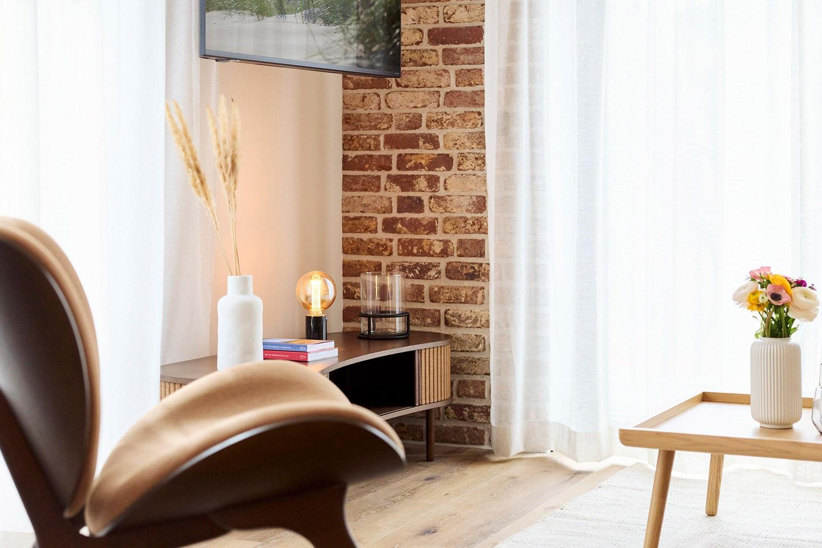 Ein Raum mit Holzboden, einer Stehlampe, einem Fernseher und einem Holztisch mit Blumen.