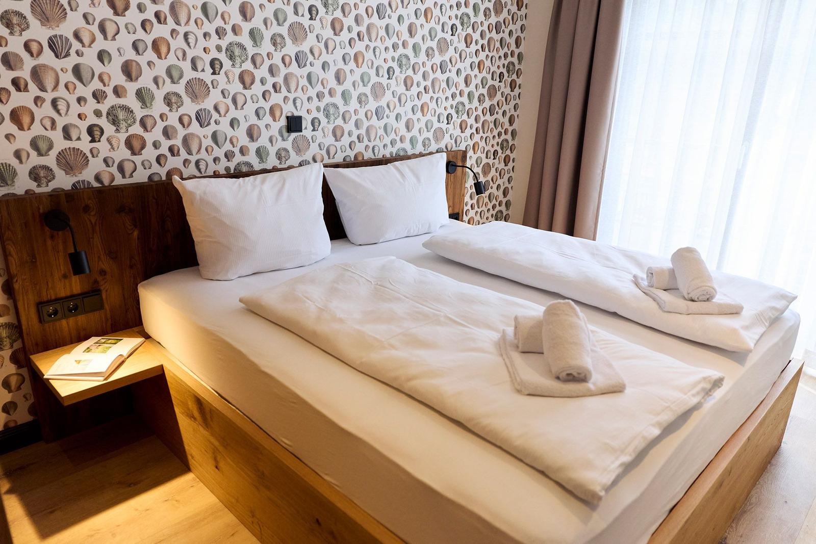 Doppelbett mit weißen Laken, Holzrahmen und Muschel壁纸