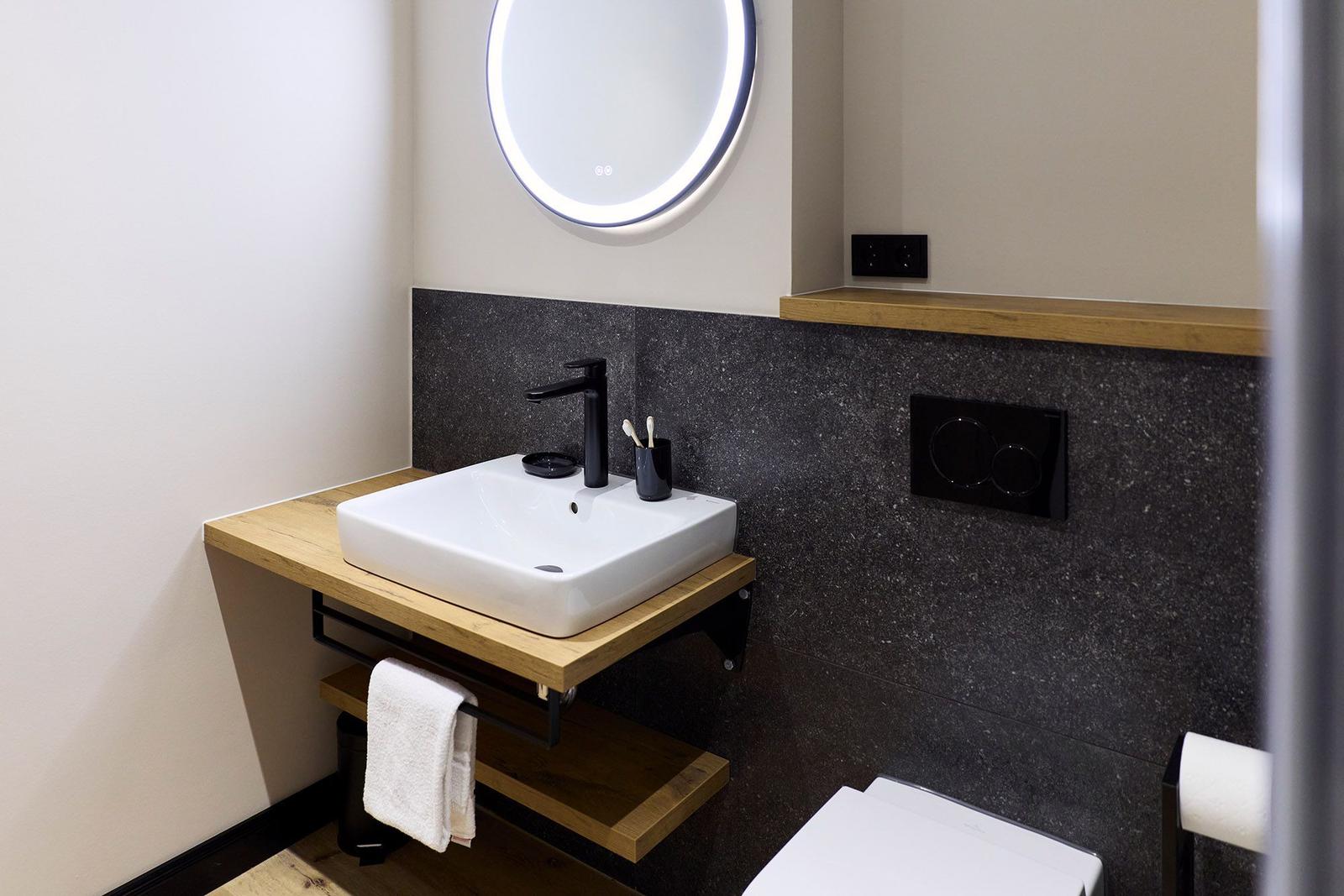 Badezimmer mit Waschbecken, Spiegel und Toilette