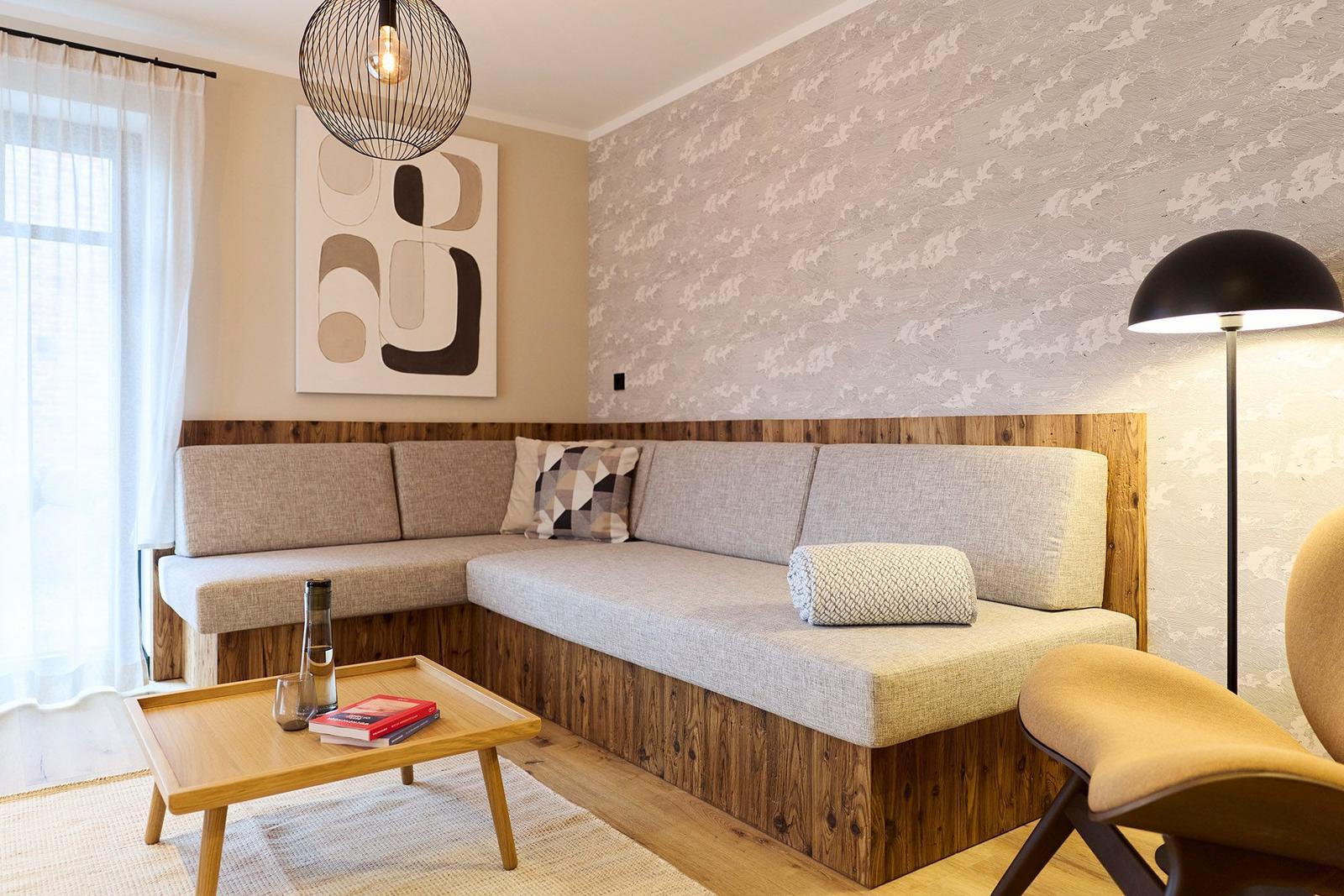Ein Wohnbereich mit Sofa, Tisch und Lampen. Wand mit Tapete und Bild.