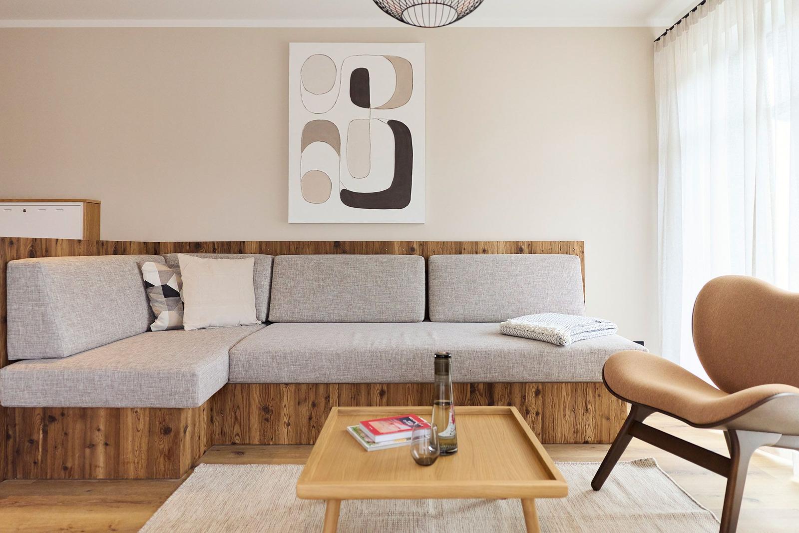 Ein Wohnzimmer mit einem grauen Sofa, einem Holztisch und einer modernen Wanddekoration.