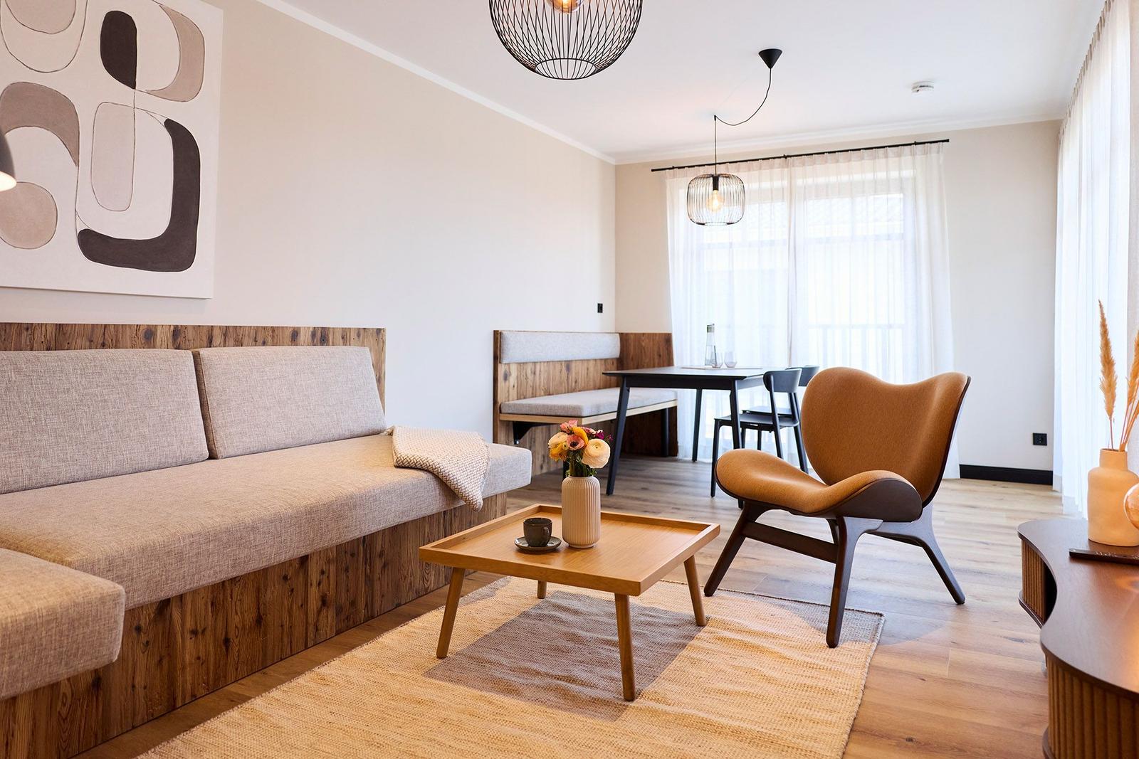Wohn- und Essbereich mit Sofa, Stuhl und Tisch. Holzboden und Wandbild.