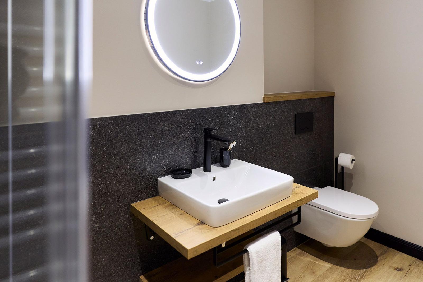 Bad mit Waschbecken auf Holz, Wandspiegel und Toilette.