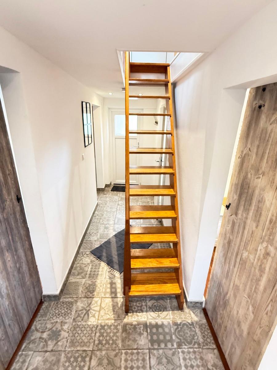 Hausflur mit Holztreppe und gemusterten Fliesen