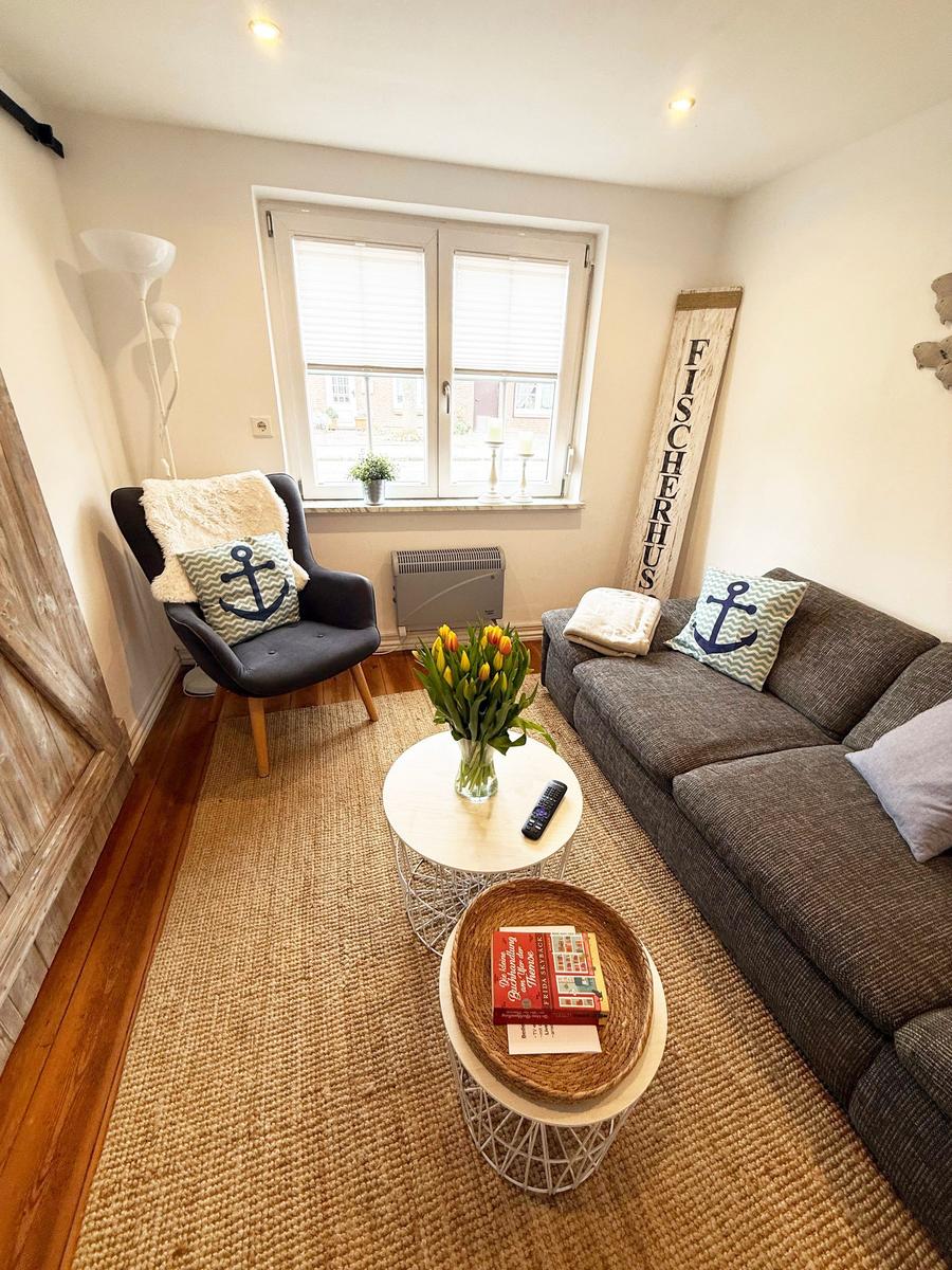 Wohnzimmer mit Sofa, Sessel, Tisch und Blumen. Wanddekoration mit Schriftzug.