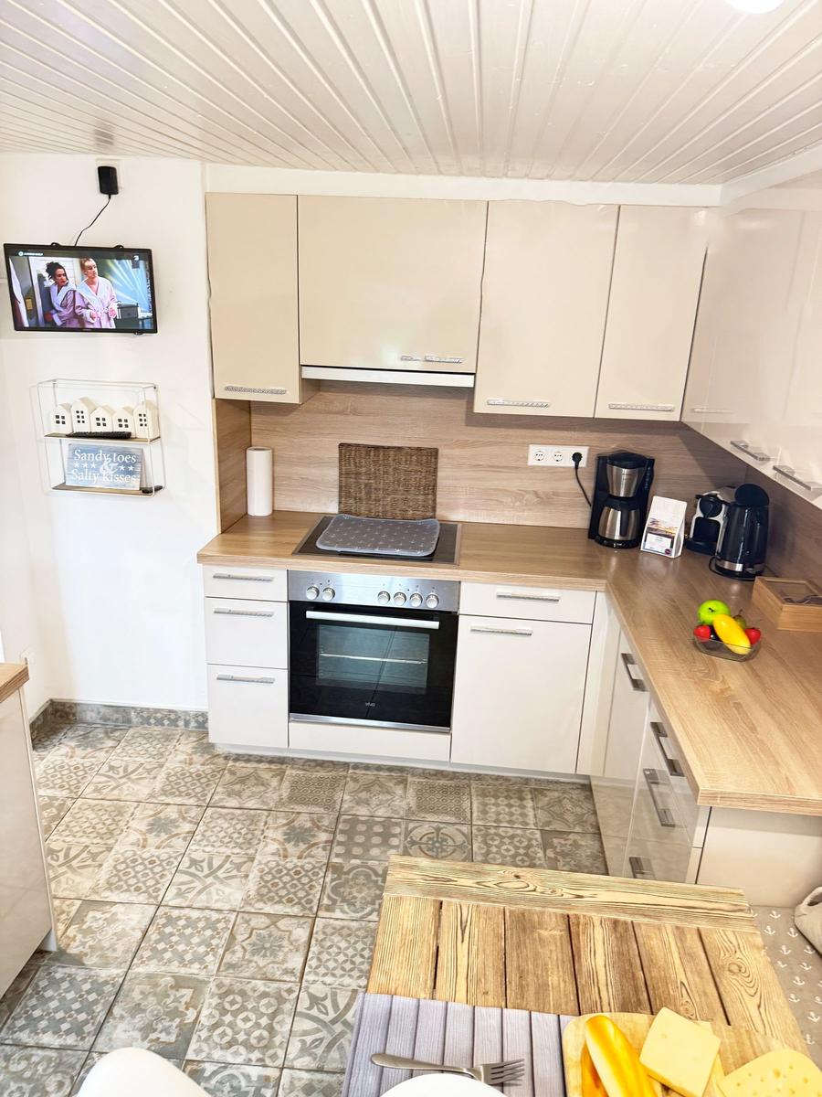 Küche mit Holzoberflächen, Kühlschrank, Herd und Fernseher an der Wand.