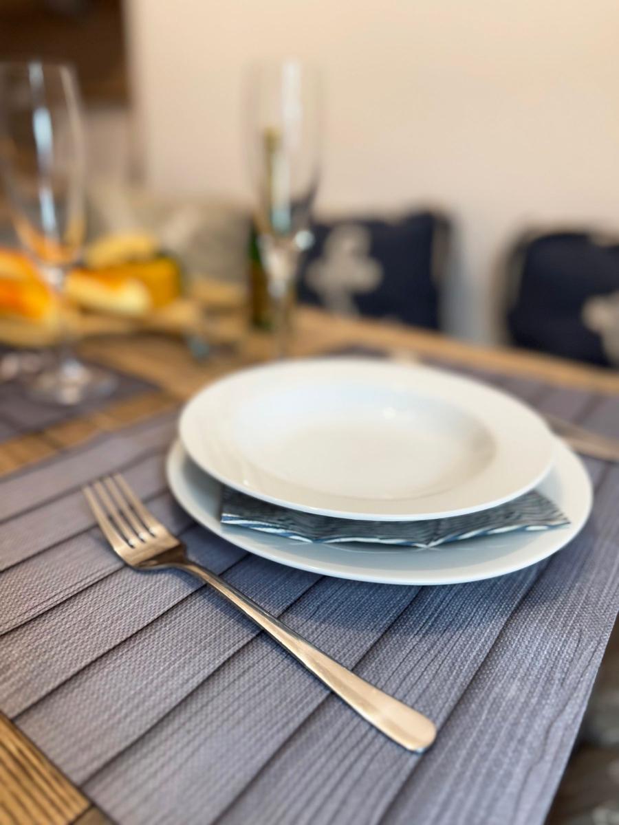Tisch mit Teller, Gabel und Gläsern auf grauem Tischset.