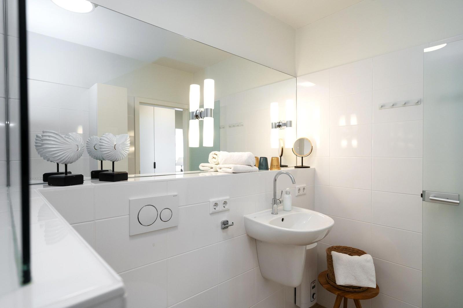 Badezimmer mit Waschbecken, Spiegel und Handtuchständer.