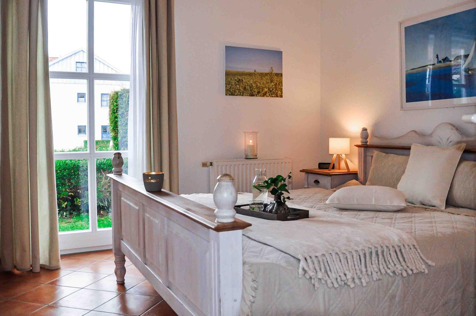 Schlafzimmer mit Bett, Nachttisch und Fenster zur Außenansicht.