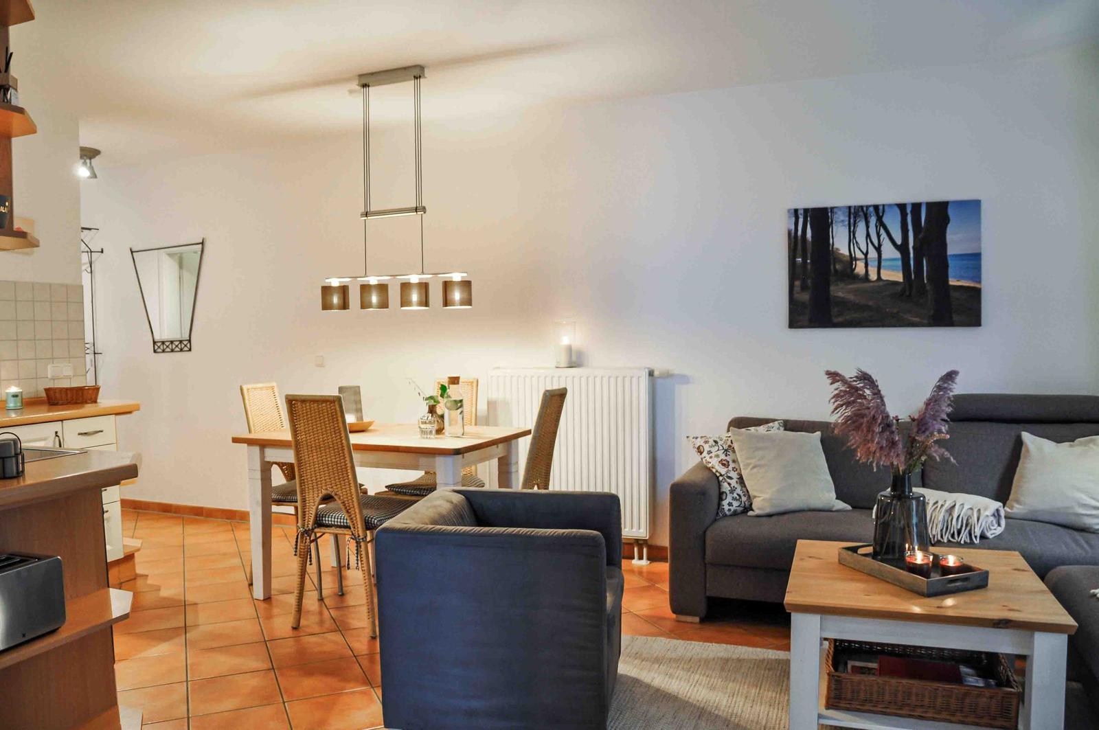 Wohn- und Essbereich mit Sofa, Tisch und Stühlen sowie Küchenbereich.