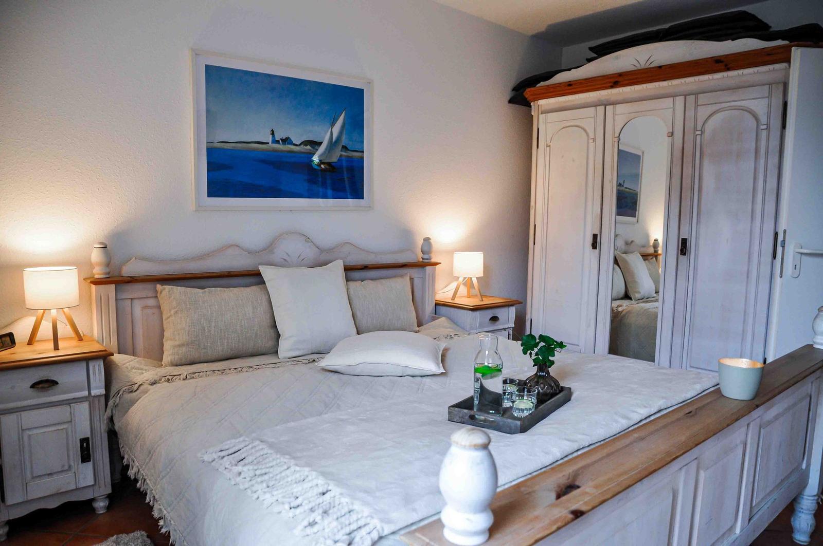 Schlafzimmer mit Bett, Nachttisch, Schrank und Wandbild.