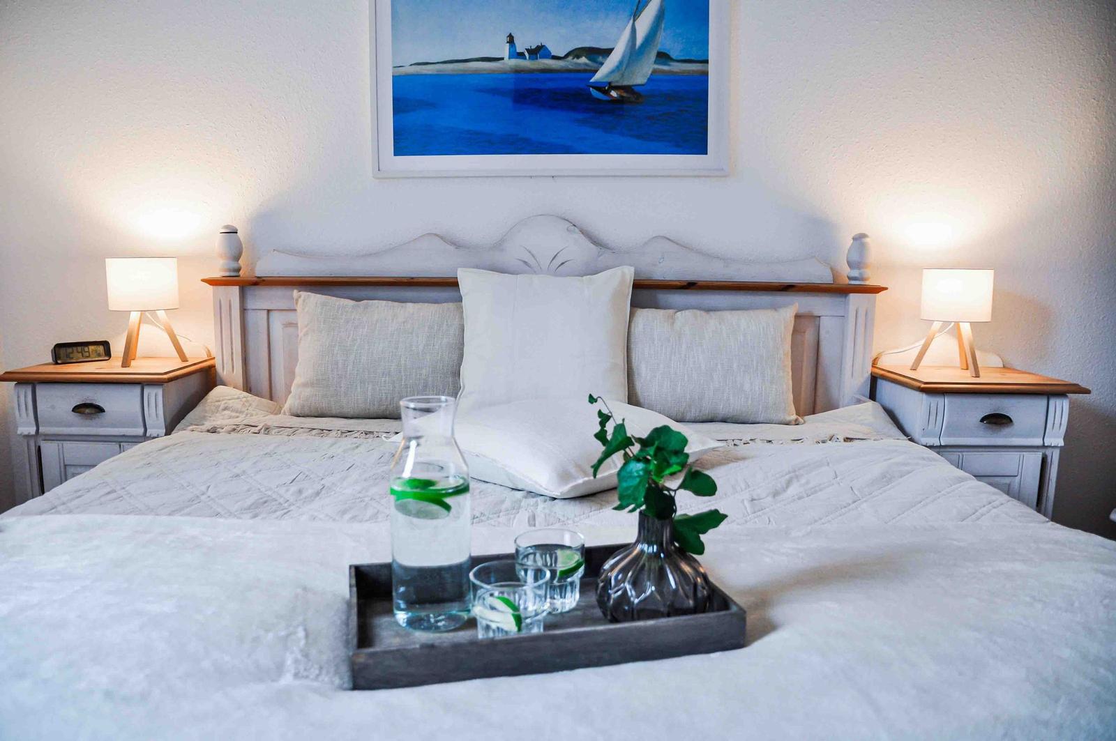 Doppelbett mit Kissen, Nachttischen und Bild an der Wand.