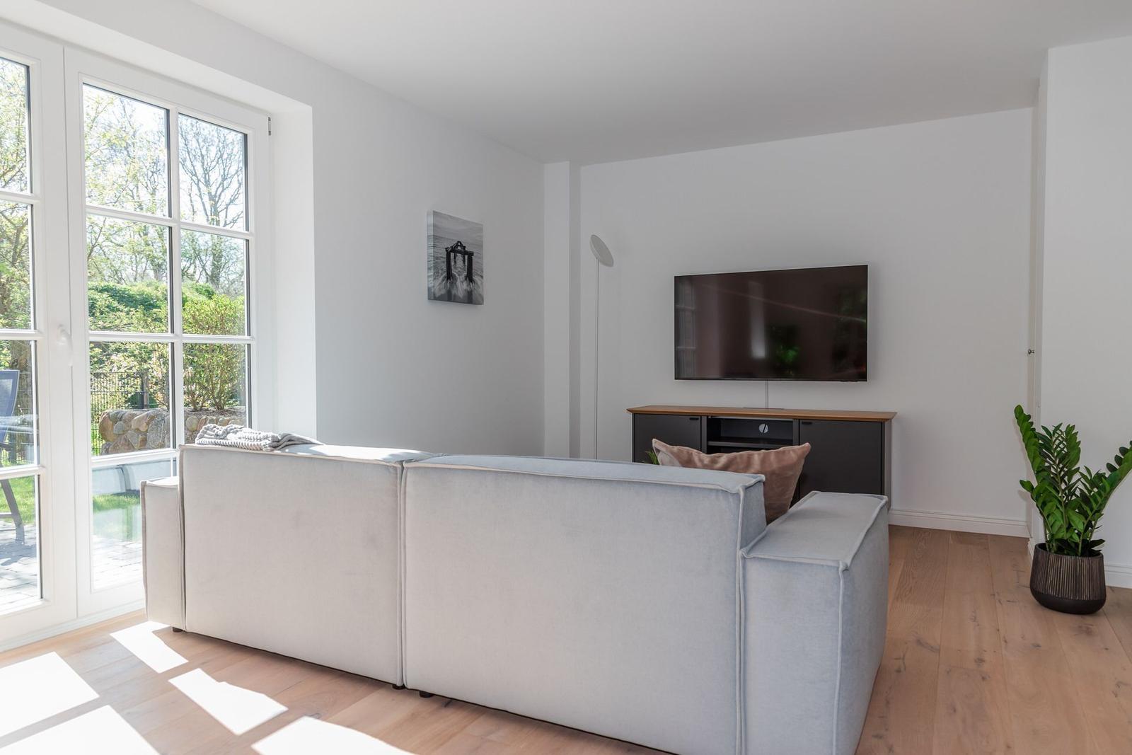 Living room with sofa, TV, and window to outdoor terrace.