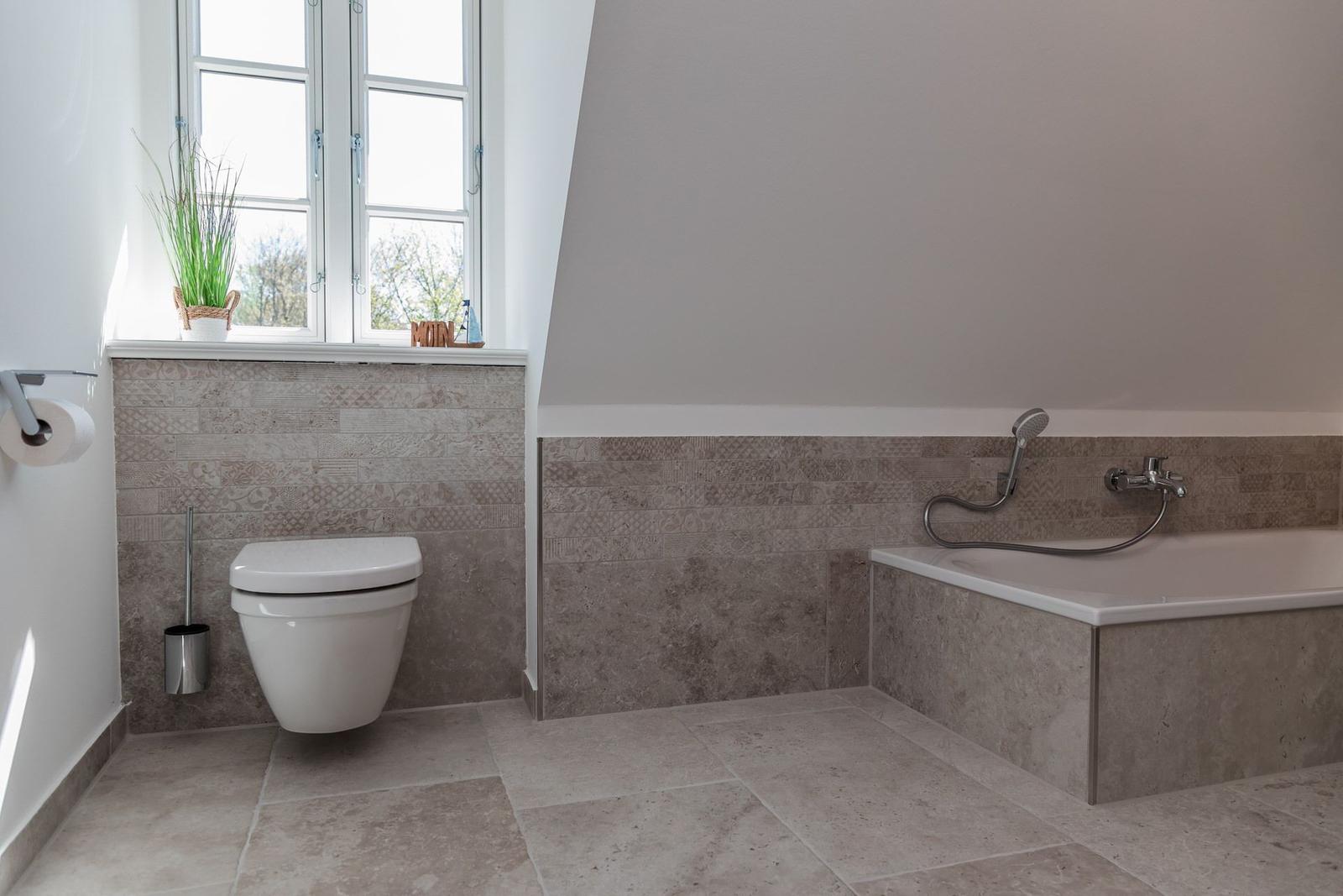Bathroom with bathtub, toilet, and window with plant.