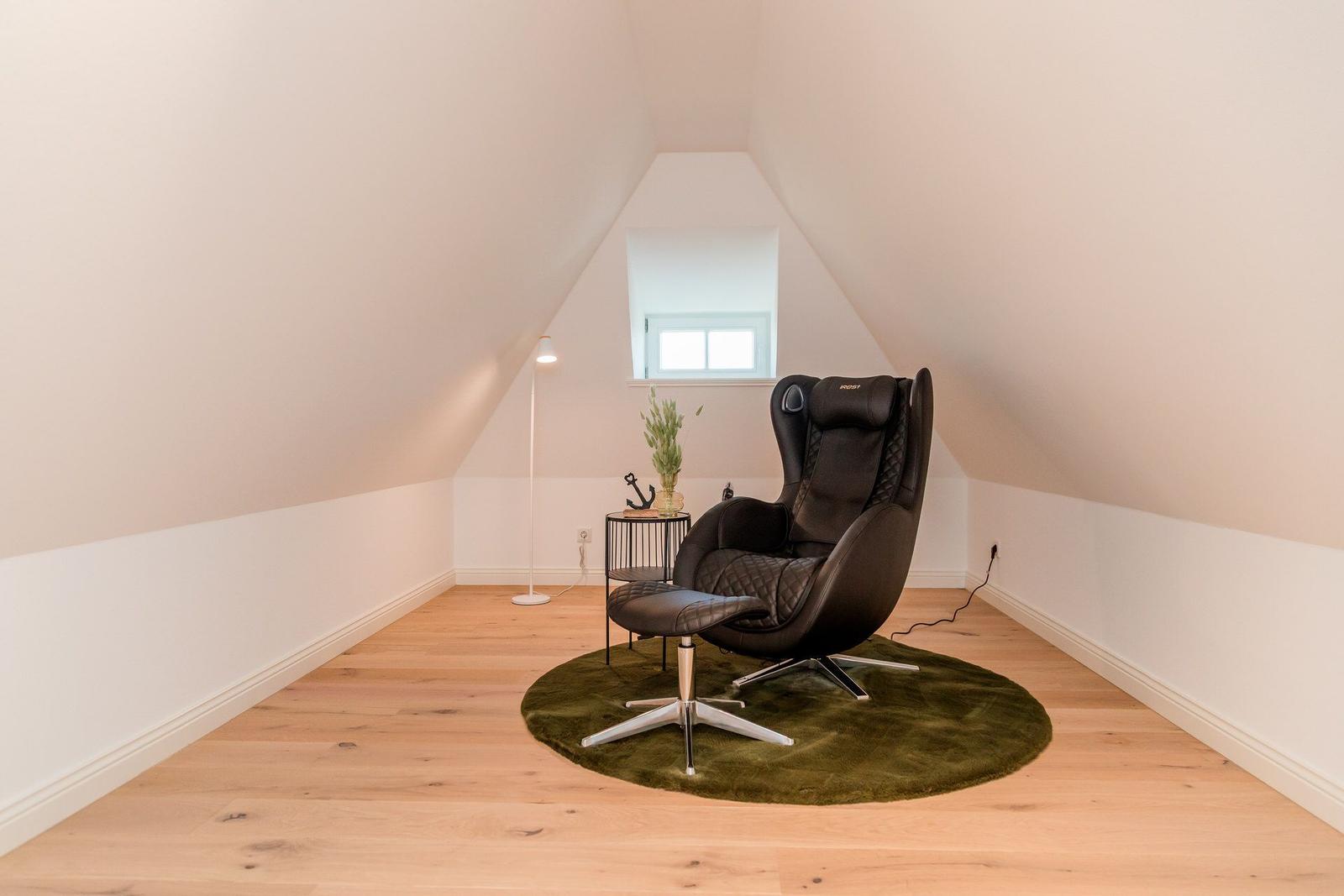 Bedroom with black chair on green rug and window