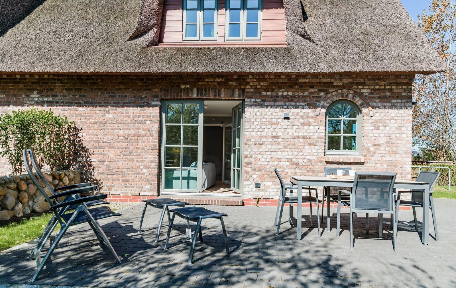 Terrace with table, chairs, and view of the house with sliding door and roof