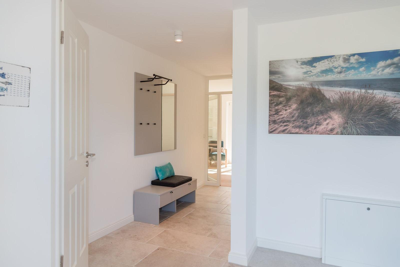 Entrance area with coat rack, bench, and wall art on the wall.