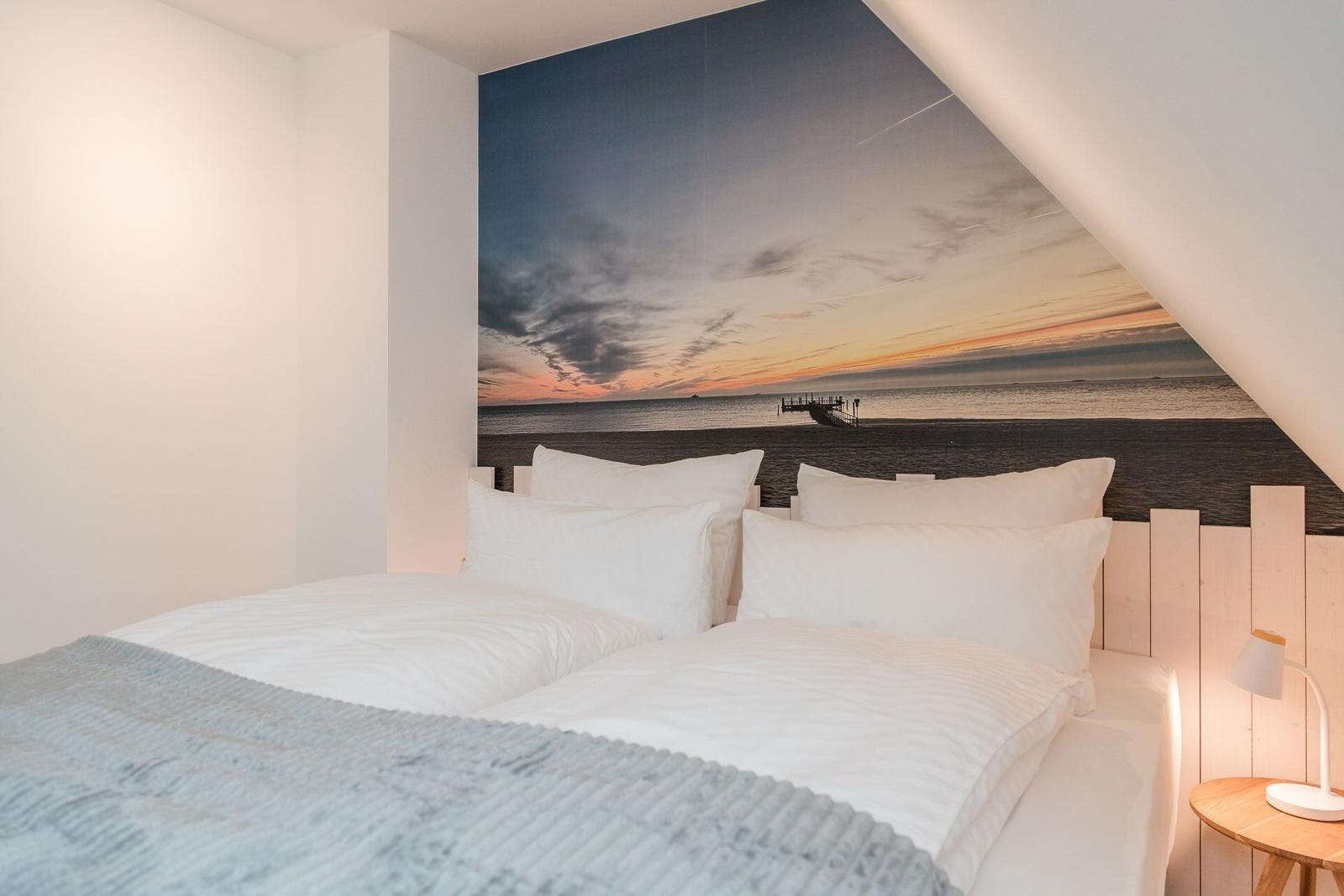 Schlafzimmer mit Bett, Wandbild und Nachttisch.