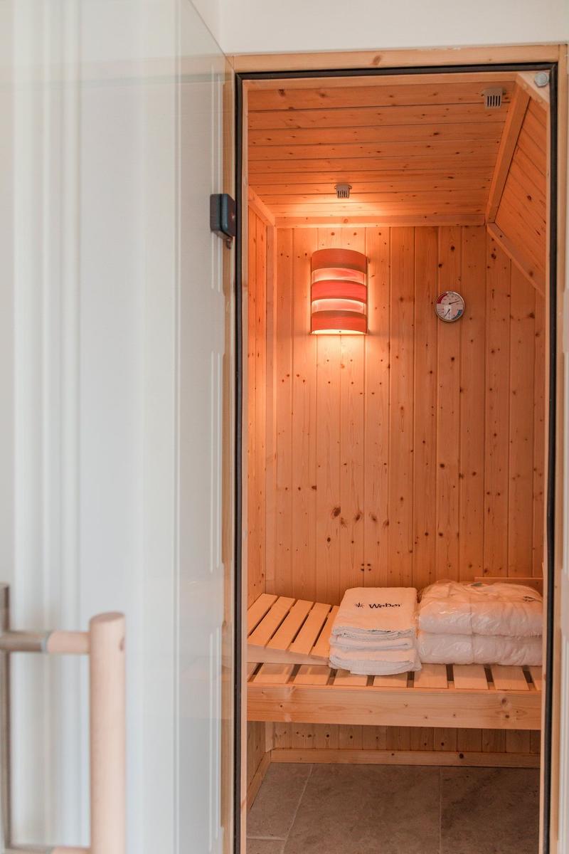 Sauna mit Holzwand, Bank, Handtuch und Thermometer.