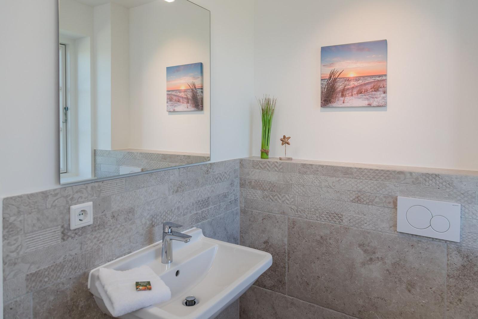 Badezimmer mit Waschbecken, Spiegel und Wandbildern
