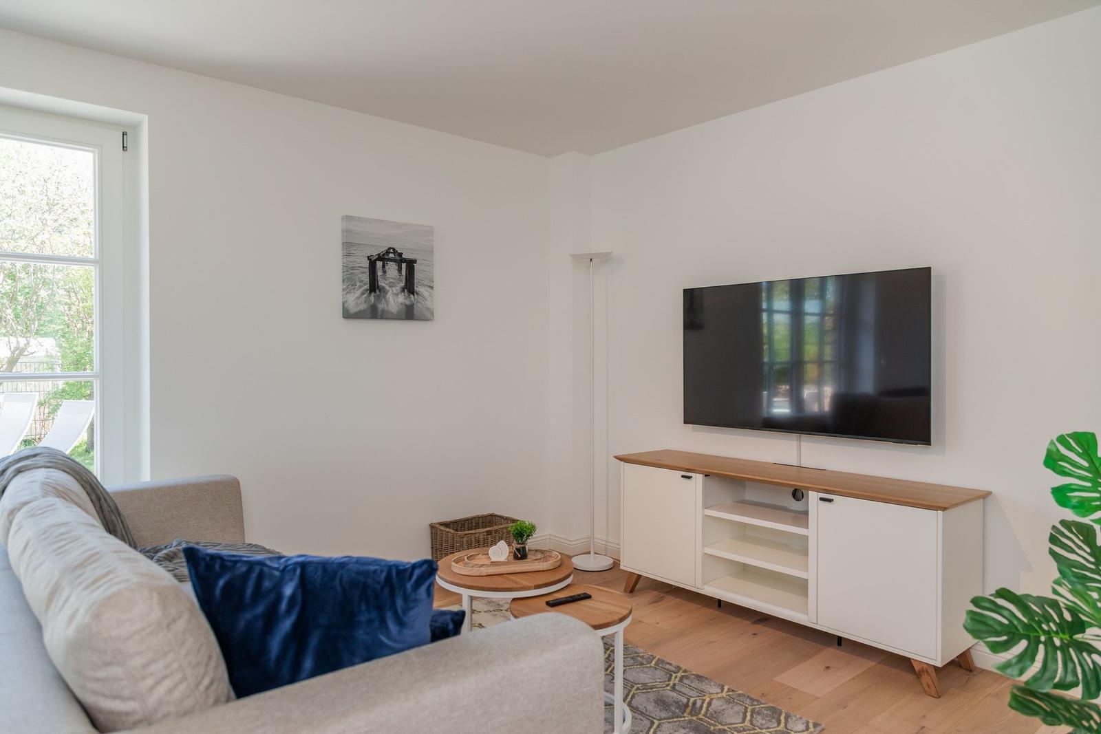 Wohnzimmer mit Sofa, Fernseher und Holzboden.