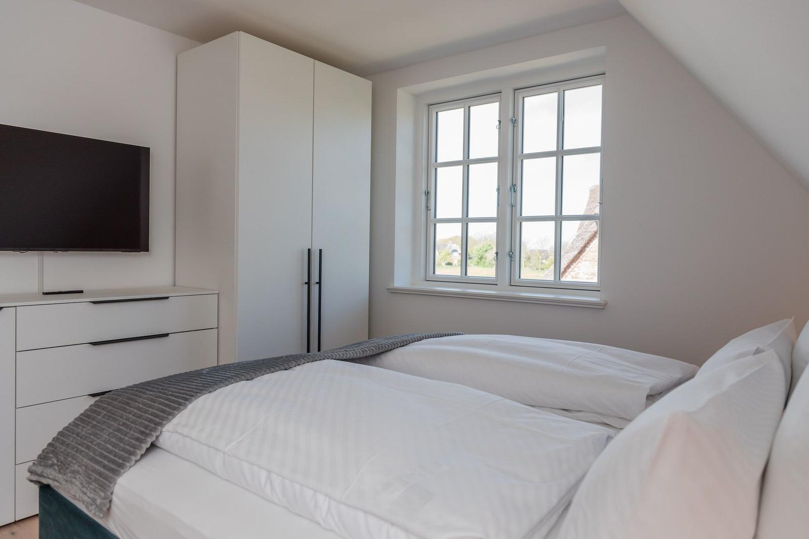 Schlafzimmer mit Doppelbett, Fenster und TV. Moderne Einrichtung.