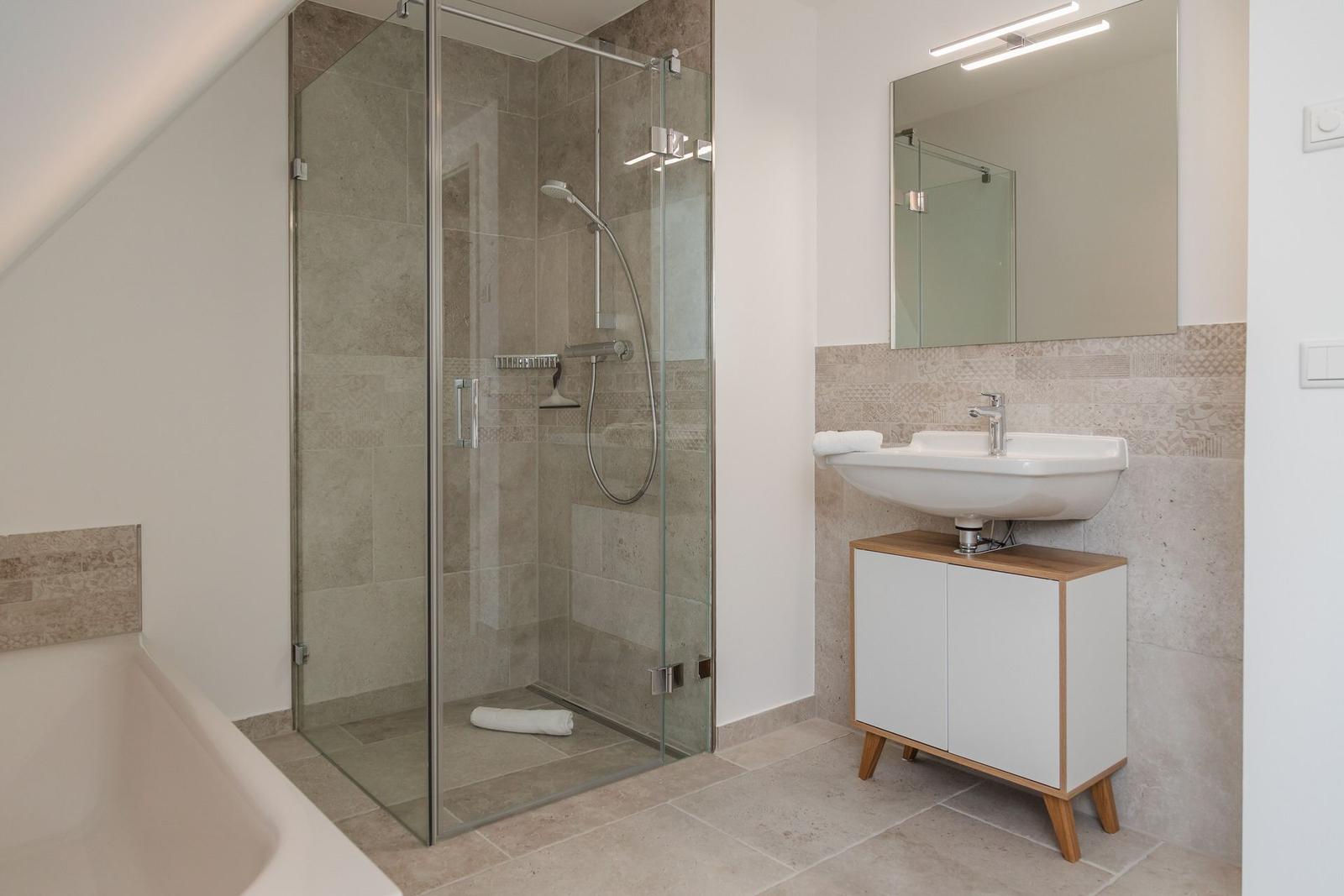 Dusche mit Glaswand, Waschbecken mit Spiegel und Badewanne