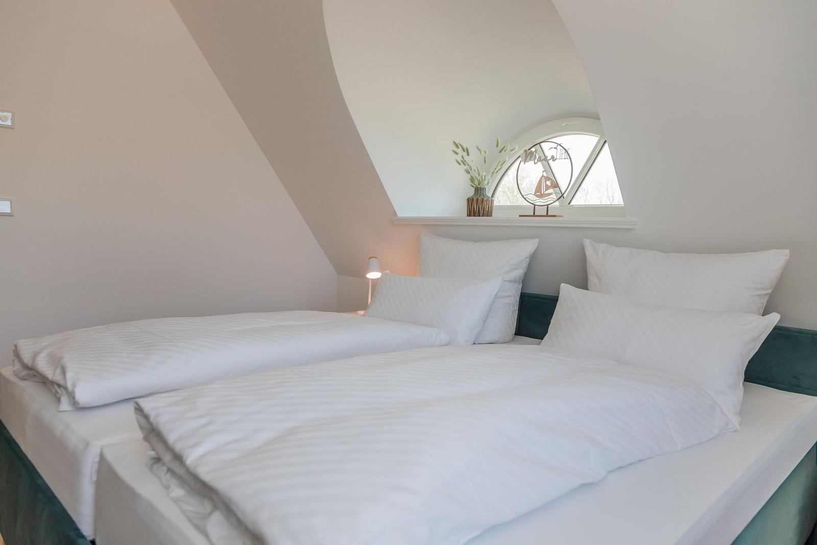 Schlafzimmer mit Doppelbett, Fenster und Nachttischlampe.