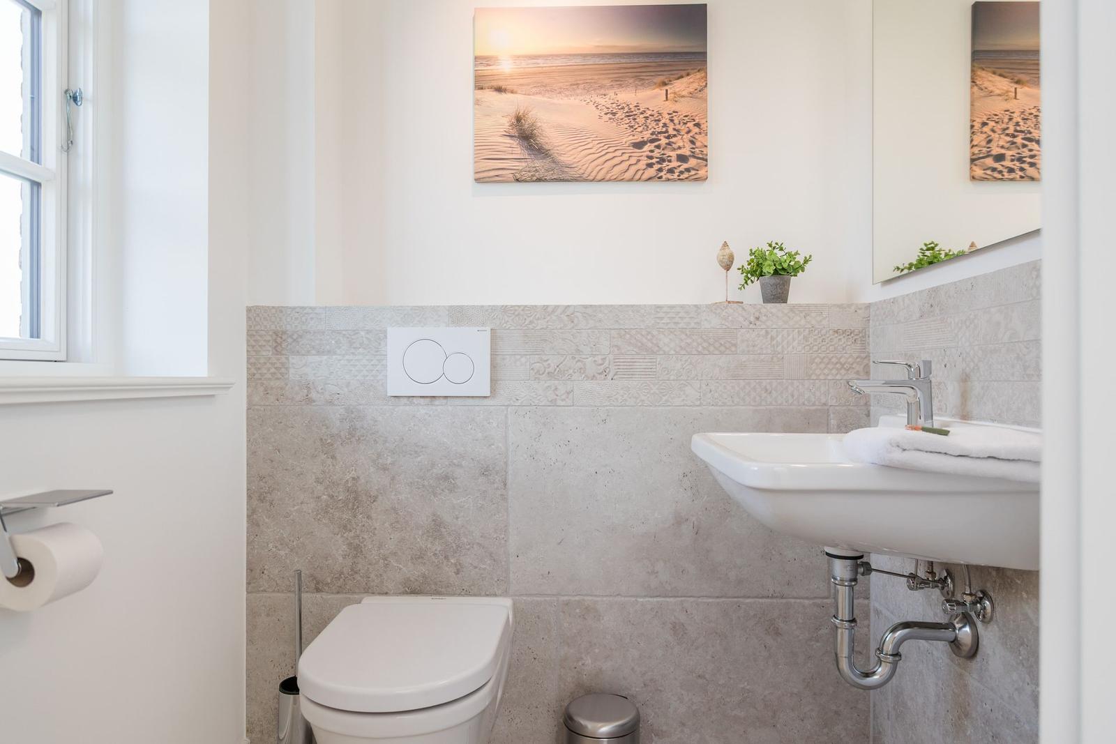 Badezimmer mit Toilette, Waschbecken und Wandbild an der Wand.