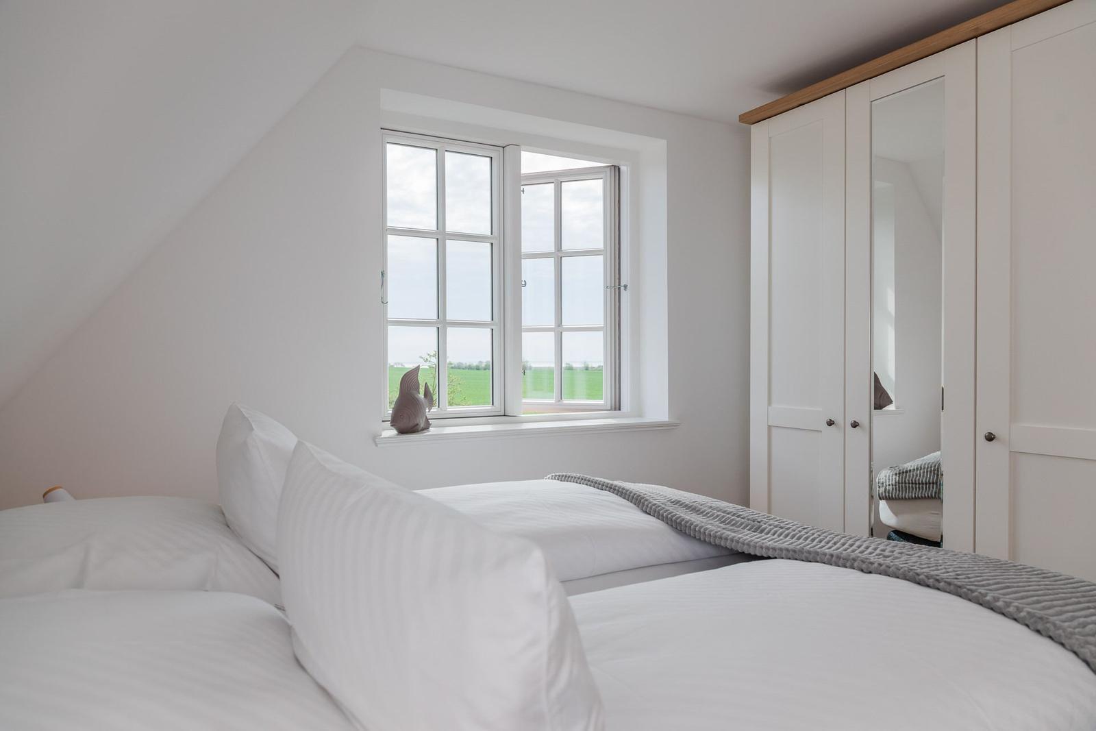 Schlafzimmer mit Dachschrägen, Fenster und Kleiderschrank.