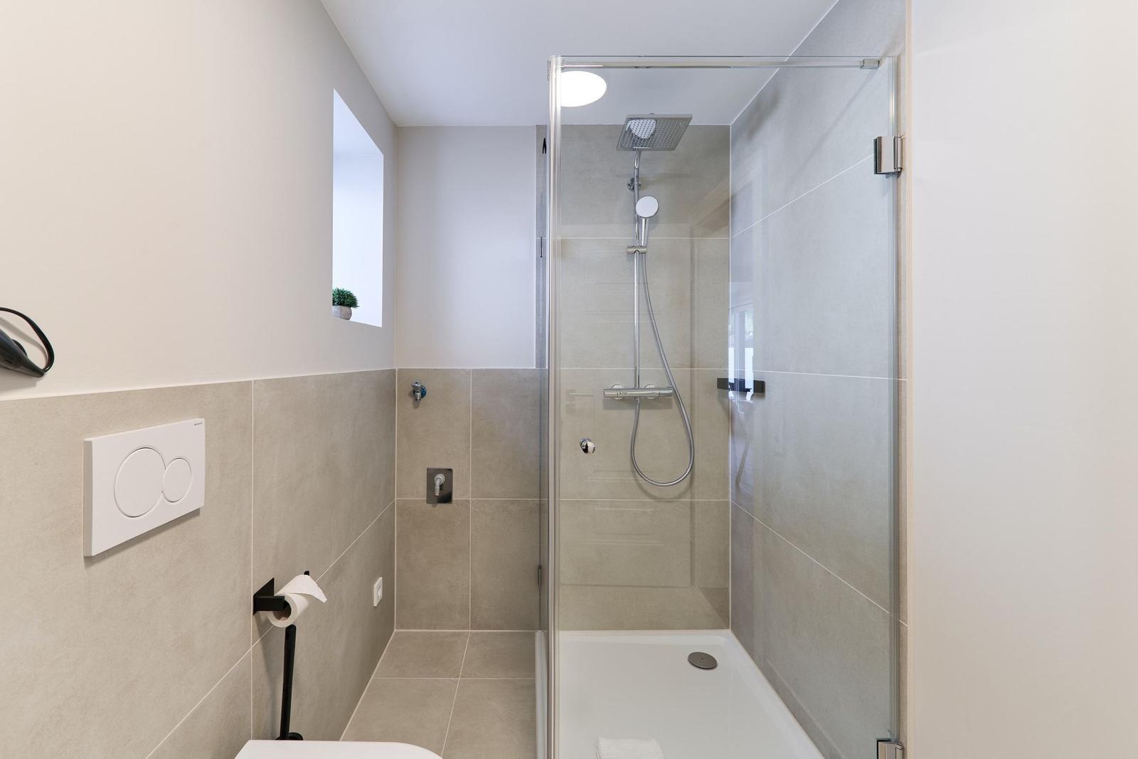Badezimmer mit Dusche, Toilette und kleinen Fenster