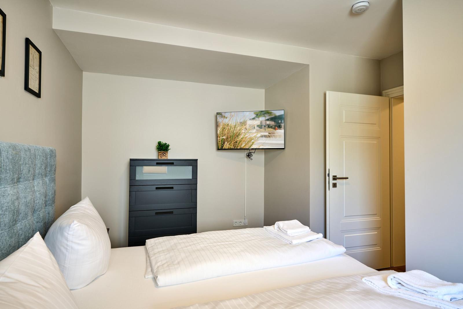 Schlafzimmer mit Bett, Schrank und Wandfernseher