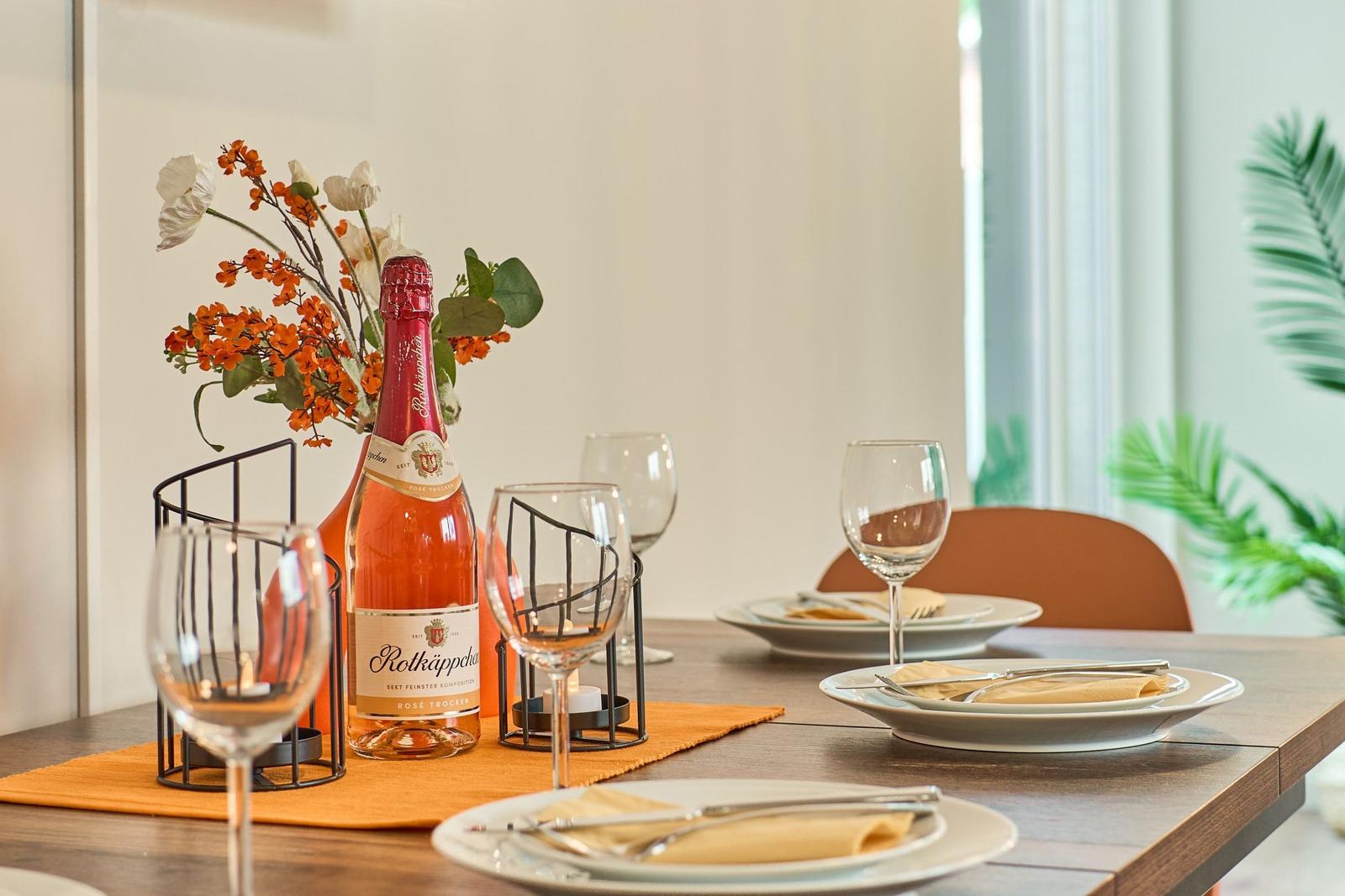 Tisch mit Weinflasche, Gläsern und Blumenarrangement