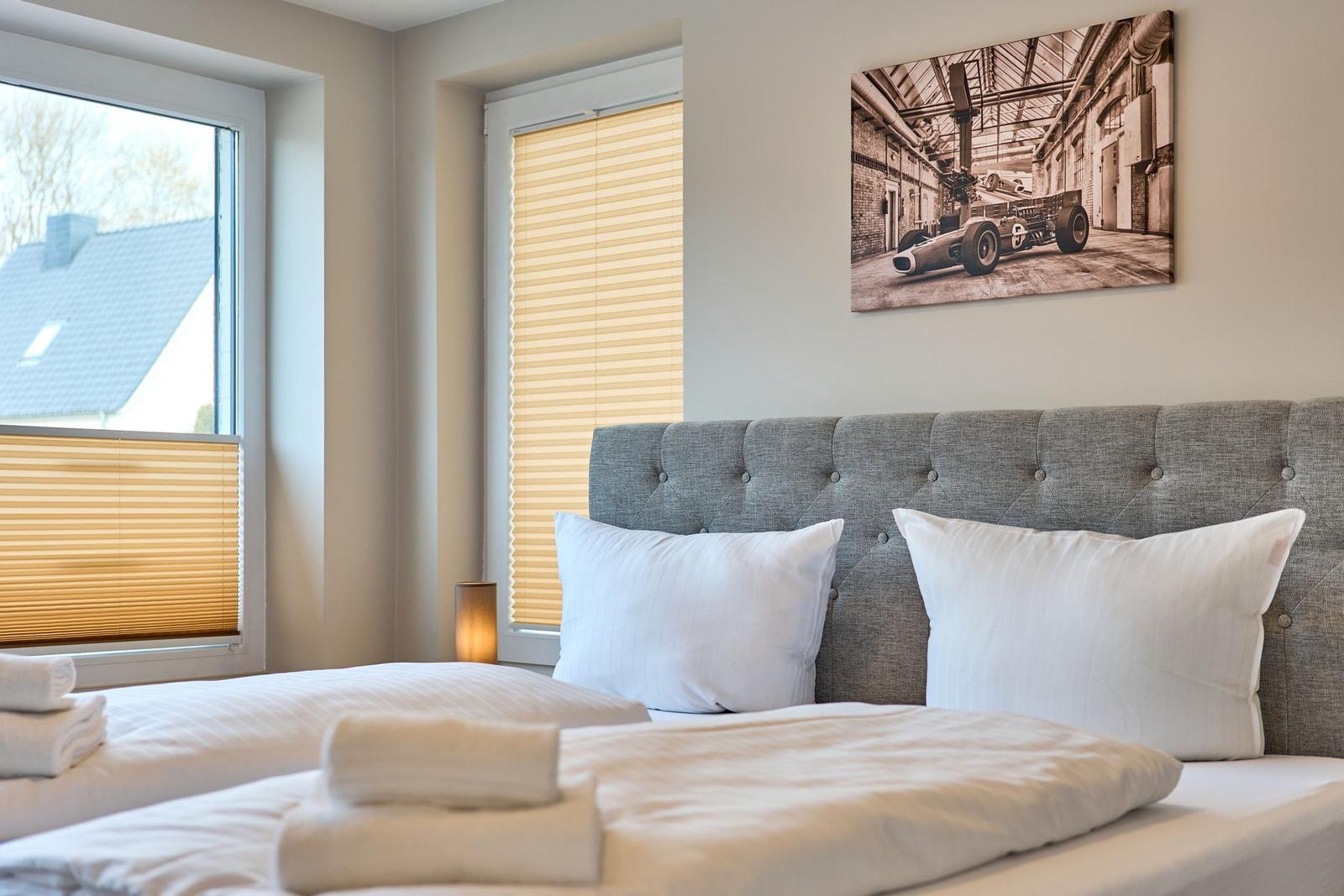 Schlafzimmer mit Bett, Fenstern und Wandbild