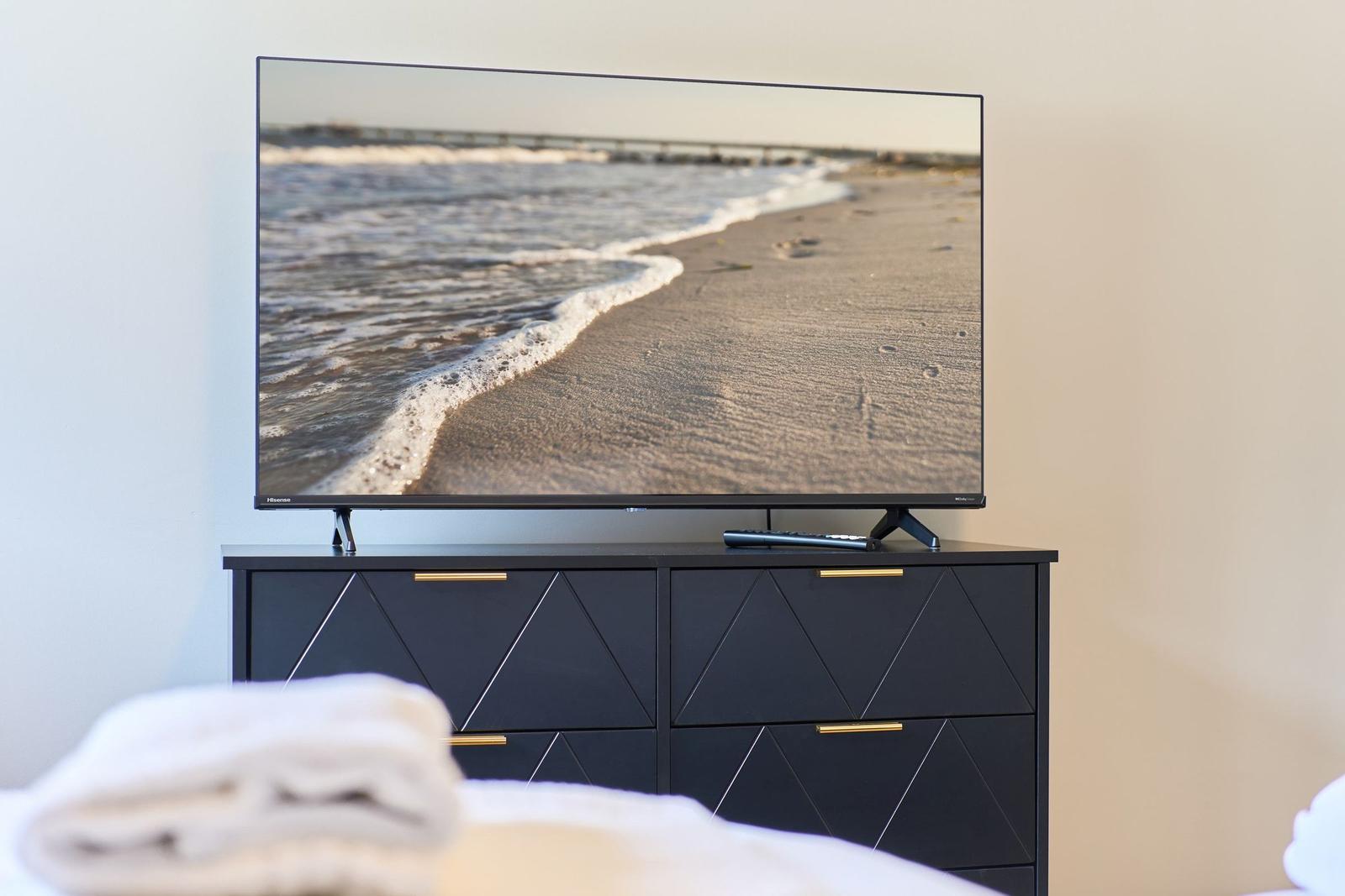 TV auf schwarzem Schrank mit goldfarbenen Griffen, Fernseher zeigt Strand