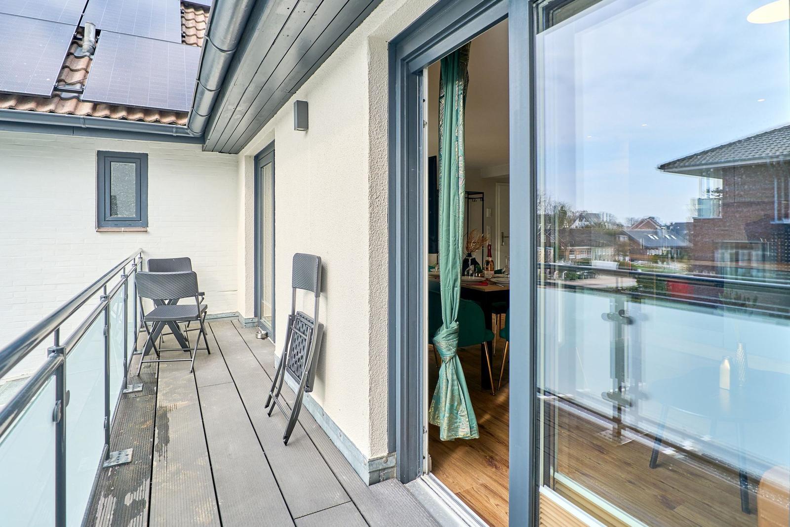 Terrasse mit Sitzgelegenheiten und Blick ins Haus. Solaranlage auf Dach.