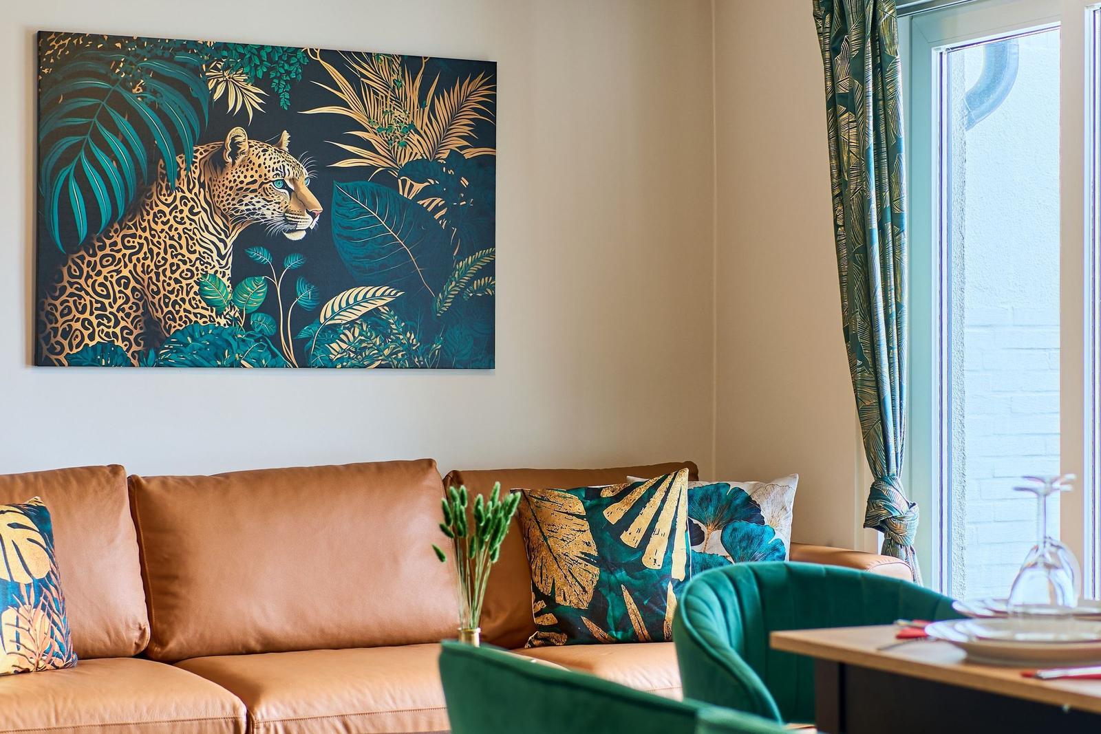 Ein Sofa mit Kissen und ein Wandbild mit einem Jaguar in tropischer Umgebung.